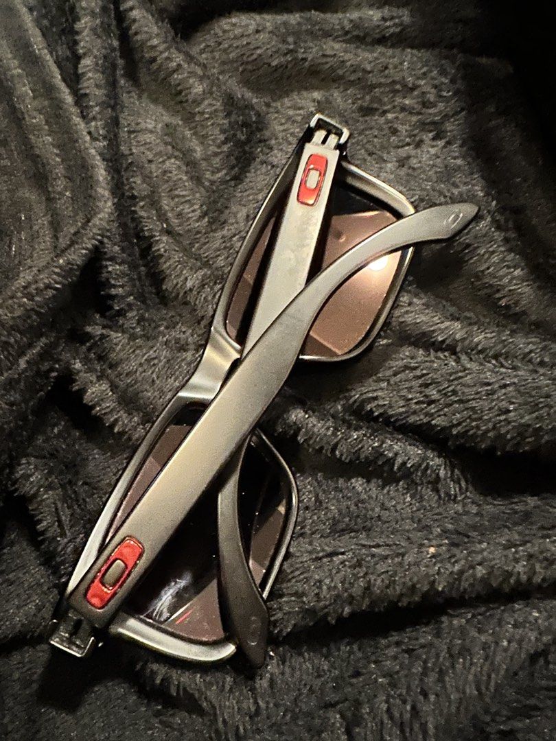 Oakley Sunglasses Red Mirror Lenses Matte Black Frame (Category: Sunglasses & Eyewear) located in Mandaluyong City. Submitted by enyaj_11 (Listing ID 1468004110, Image 3). Description: - Brand: Oakley sunglasses - Frame: Matte black with classic square shape - Lenses: Striking red mirror lenses - Details: Iconic red O-logo icons on the temples - Condition: Fully functional; note noticeable wear and flaking along the inner edge of the right lens n