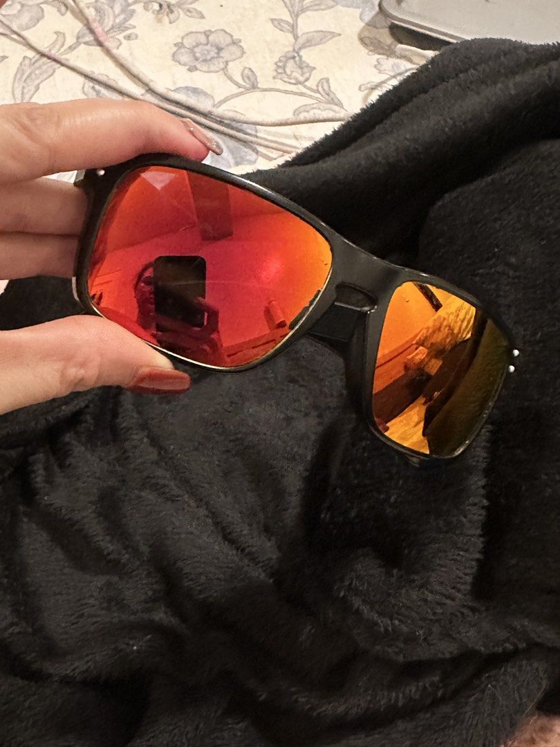 Oakley Sunglasses Red Mirror Lenses Matte Black Frame (Category: Sunglasses & Eyewear) located in Mandaluyong City. Submitted by enyaj_11 (Listing ID 1468004110, Image 2). Description: - Brand: Oakley sunglasses - Frame: Matte black with classic square shape - Lenses: Striking red mirror lenses - Details: Iconic red O-logo icons on the temples - Condition: Fully functional; note noticeable wear and flaking along the inner edge of the right lens n