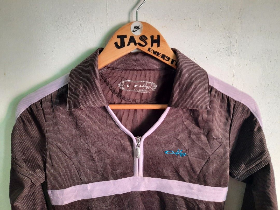 Oakley Vintage Quarter Zip Pullover Brown Purple (Category: Coats, Jackets and Outerwear) located in City of Isabela. Submitted by jasheverything (Listing ID 1467942113, Image 2). Description: - Brand: Oakley - Style: Quarter-zip pullover with collared neckline - Size: Small - Color: Brown and purple with contrast purple piping and midsection band - Logo: Bright blue embroidered Oakley logo on the chest - Material/Texture: Striped ribbed fabric t