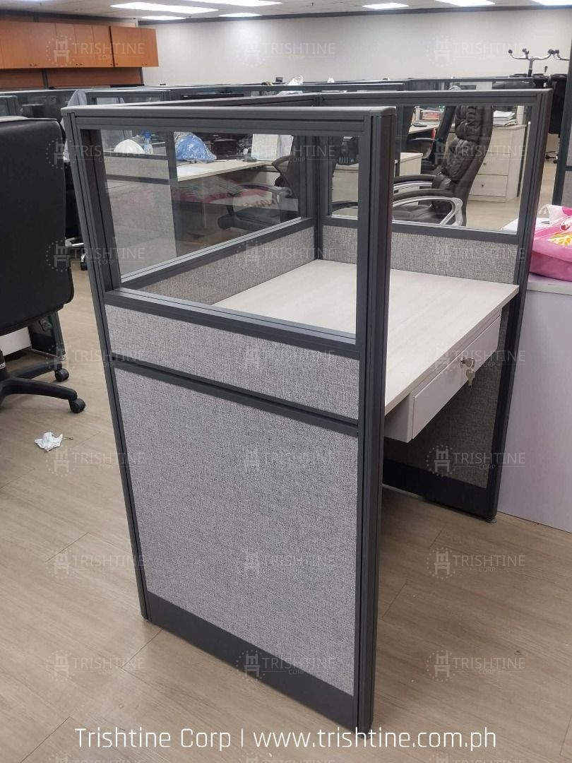 Office Workstation Cubicle Partition Desk (Category: Office Furniture & Fixtures) located in Caloocan City. Submitted by jim.trishtineofficefurnitures (Listing ID 1467887872, Image 1). Description: - Modular office cubicle designed for call centers and open layouts - Stylish grey fabric panels with modern glass top dividers - Durable light wood grain desktop featuring a convenient pull-out drawer - Built-in cable management grommet hole to keep w