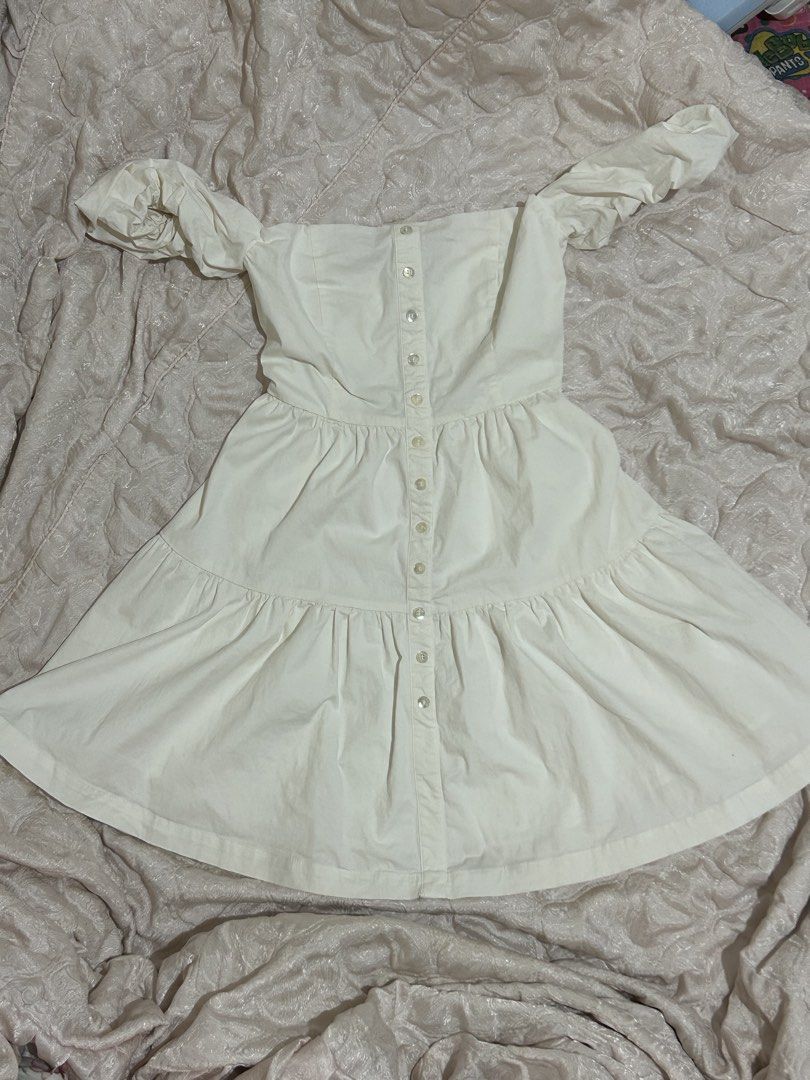 Off-shoulder beige button-front mini dress (Category: Dresses) located in Tuguegarao City. Submitted by eliwyxzs (Listing ID 1467840961, Image 2). Description: - Color: Light cream / beige - Style: Off-shoulder mini dress with puffy short sleeves - Details: Functional front button closure, fitted bodice, and a tiered flared skirt - Fit: Structured and flattering - Occasion: Ideal for casual days out and weekend wear.