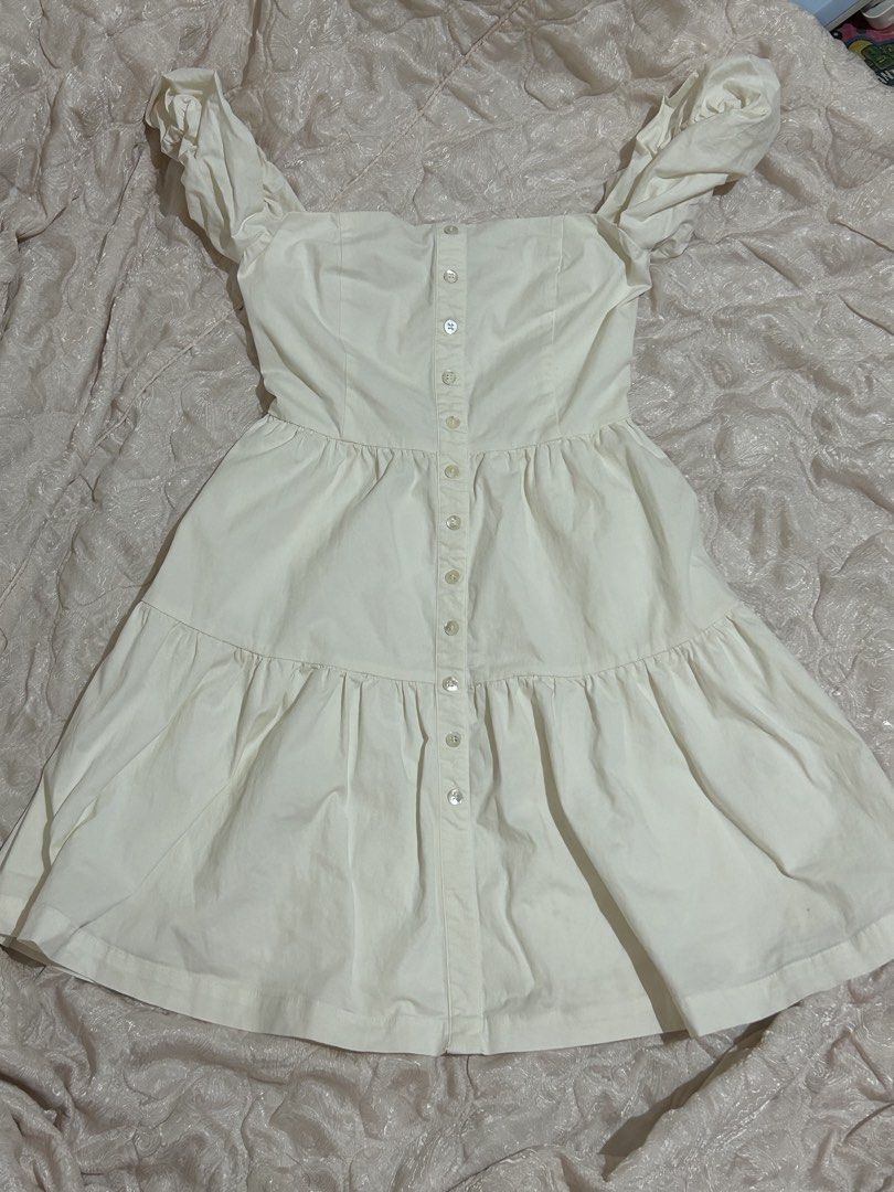 Off-shoulder beige button-front mini dress (Category: Dresses) located in Tuguegarao City. Submitted by eliwyxzs (Listing ID 1467840961, Image 3). Description: - Color: Light cream / beige - Style: Off-shoulder mini dress with puffy short sleeves - Details: Functional front button closure, fitted bodice, and a tiered flared skirt - Fit: Structured and flattering - Occasion: Ideal for casual days out and weekend wear.