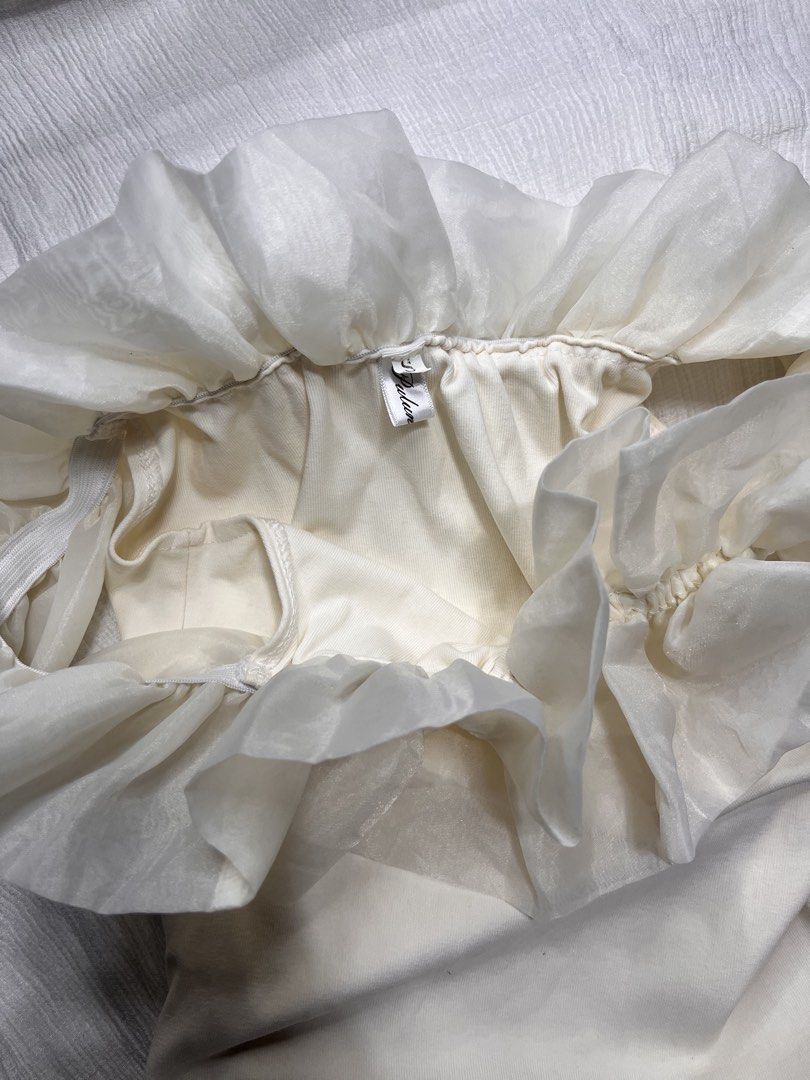 Off-shoulder Ruffle Cream Dress (Category: Dresses) located in General Mariano Alvarez. Submitted by kascade (Listing ID 1468051420, Image 3). Description: - Color: Cream-white off-shoulder - Size: S (tag attached) - Fit: Bodycon with flattering side ruching - Details: Layered sheer ruffles at the neckline, side zip closure - Material: Soft and stretchy fabric - Condition: Excellent, worn only a couple of times - Ideal for: Parties, dates, and di