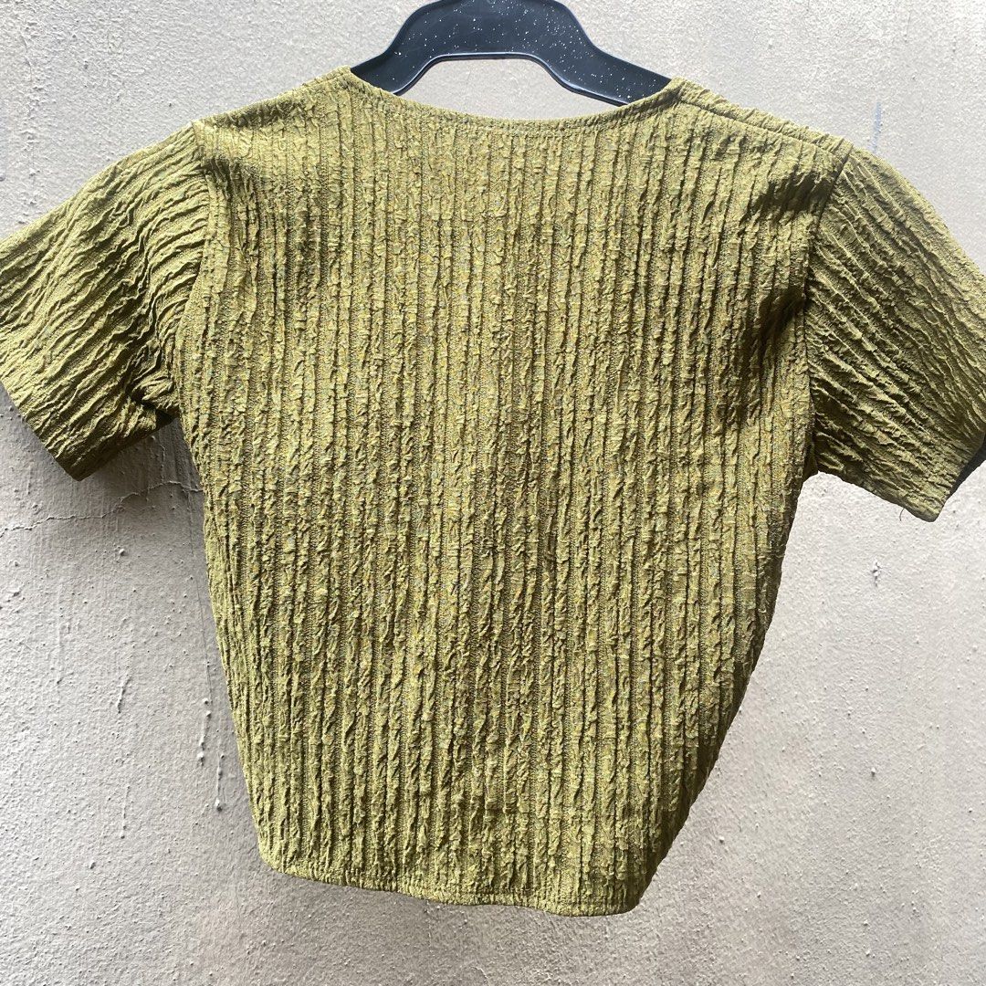 Olive green crinkle crop top with front twist (Category: Shirts) located in Muntinlupa City. Submitted by 4eva3volve (Listing ID 1467946636, Image 3). Description: - Color: Green - Style: Crop top with deep V-neckline, short sleeves, and front twist knot detail - Texture: Crinkled texture all over (front and back) - Fit & Fabric: Lightweight, stretchy, and comfortable - Condition: Like new, worn only once or twice - Care: Machine washable.
