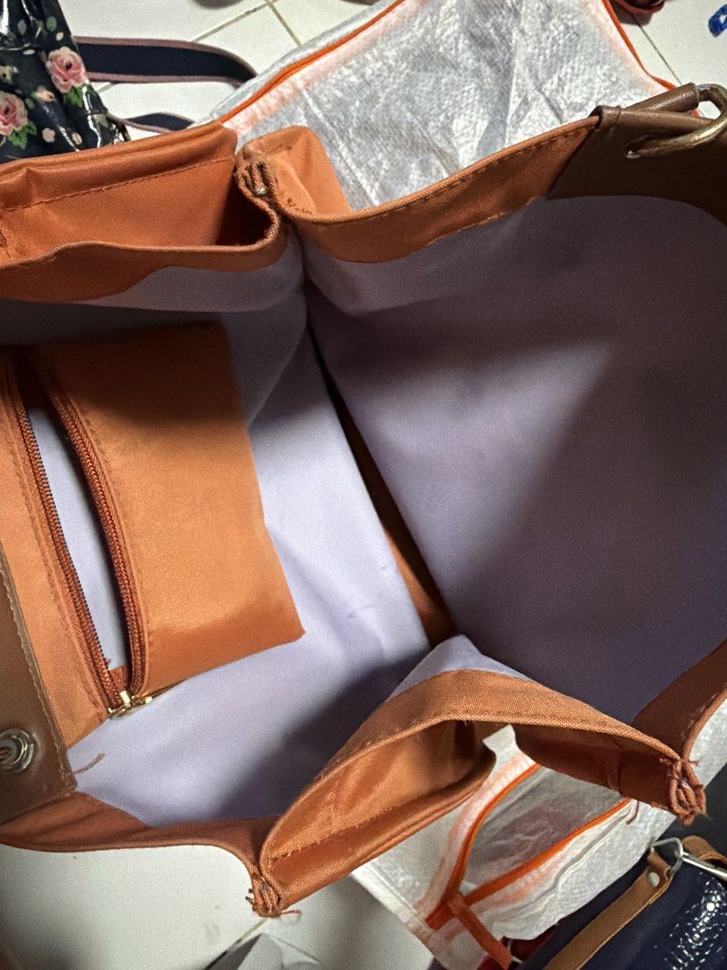 Orange nylon tote bag with brown flap (Category: Tote Bags) located in Manila. Submitted by bitski (Listing ID 1467973286, Image 2). Description: - Color: Vibrant orange nylon with chic brown faux leather straps and flap closure - Interior: Pretty light purple lining with a handy zippered pocket for small items - Capacity: Spacious main compartment easily fits your everyday essentials - Details: Sturdy grab handles attached with stylish metal rin