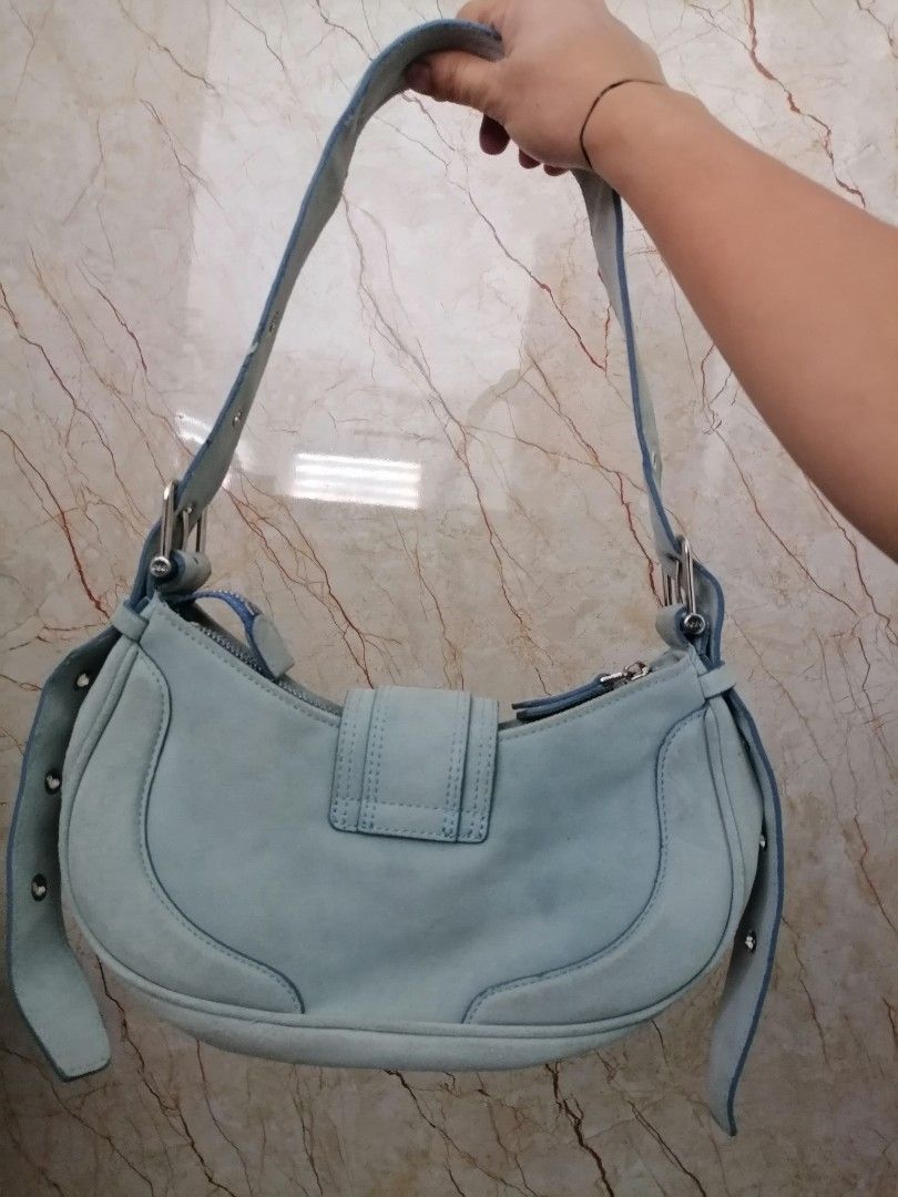 Osoi Suede Shoulder Bag Light Blue (Category: Shoulder Bags) located in Digos. Submitted by crodualady82694 (Listing ID 1467880508, Image 2). Description: - Brand: Osoi - Material: Suede - Color: Light Blue - Design: Sleek crescent silhouette with clean lines - Hardware: Chunky silver buckle strap with eyelet detailing and stamped logo - Closure: Secure zip top - Interior: Lined with a convenient slip pocket - Condition: Excellent overall shape.