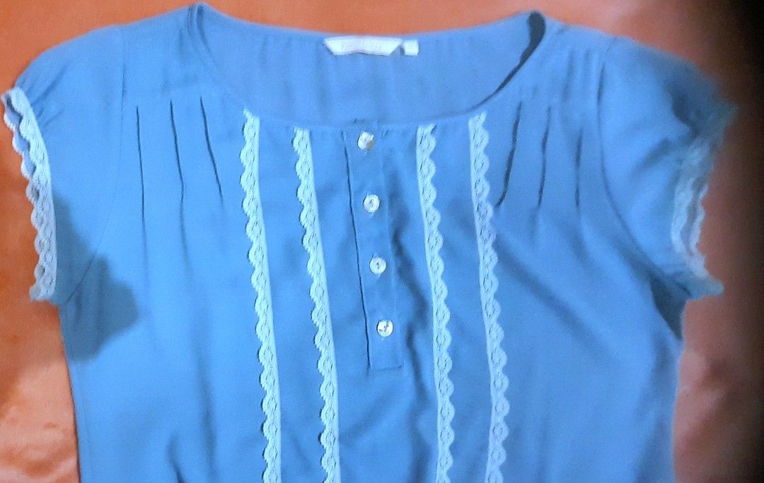 Paper Dolls Blue Lace Trim Button Blouse Medium (Category: Blouses) located in Manila. Submitted by declutter.mnla (Listing ID 1467999605, Image 2). Description: - Brand: Paper Dolls - Size: M - Color: Light blue - Details: Front button placket with 4 pearlescent buttons, white lace trim panels on the chest, gathered neckline, and elasticated drawstring hem - Style: Cute and casual, perfect for warm weather - Condition: Excellent.