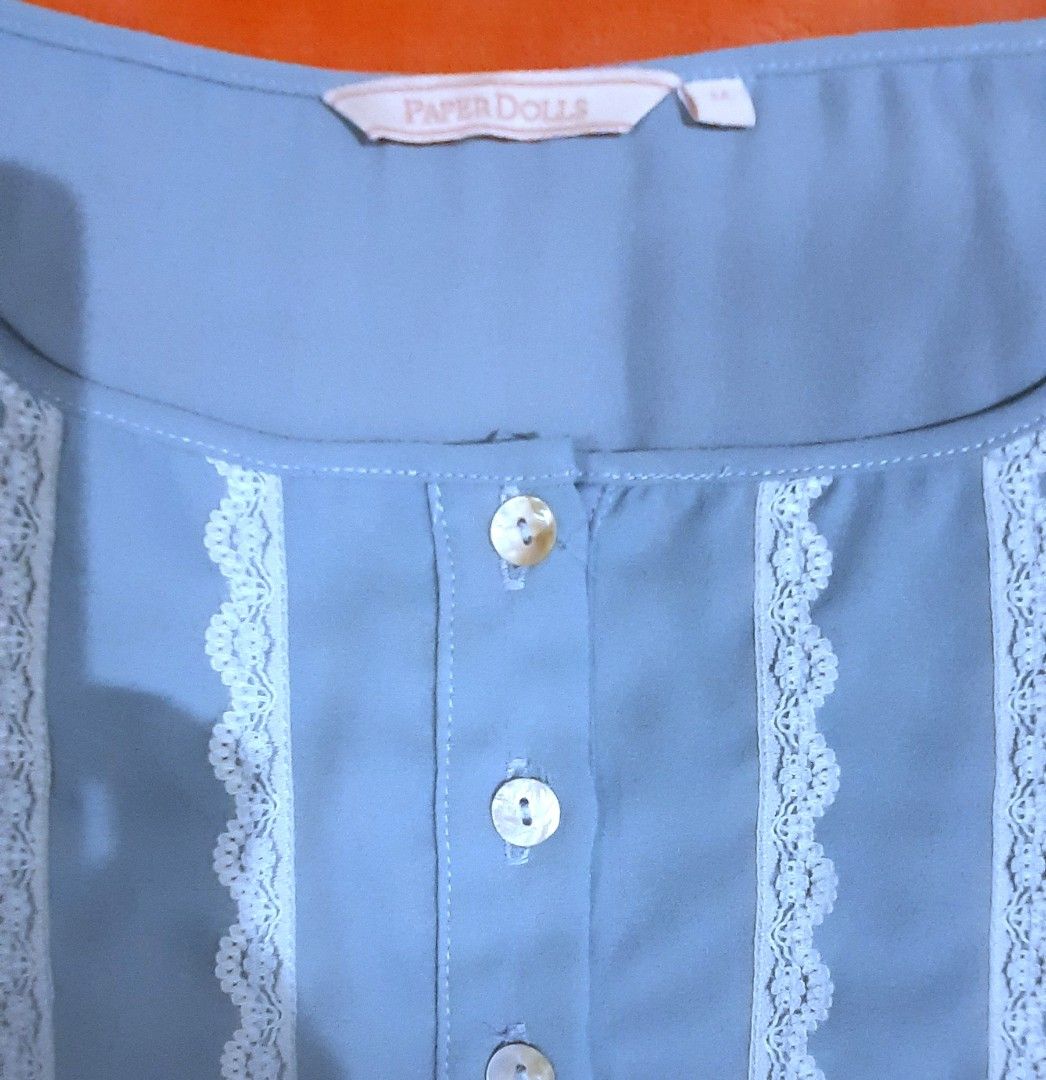 Paper Dolls Blue Lace Trim Button Blouse Medium (Category: Blouses) located in Manila. Submitted by declutter.mnla (Listing ID 1467999605, Image 3). Description: - Brand: Paper Dolls - Size: M - Color: Light blue - Details: Front button placket with 4 pearlescent buttons, white lace trim panels on the chest, gathered neckline, and elasticated drawstring hem - Style: Cute and casual, perfect for warm weather - Condition: Excellent.