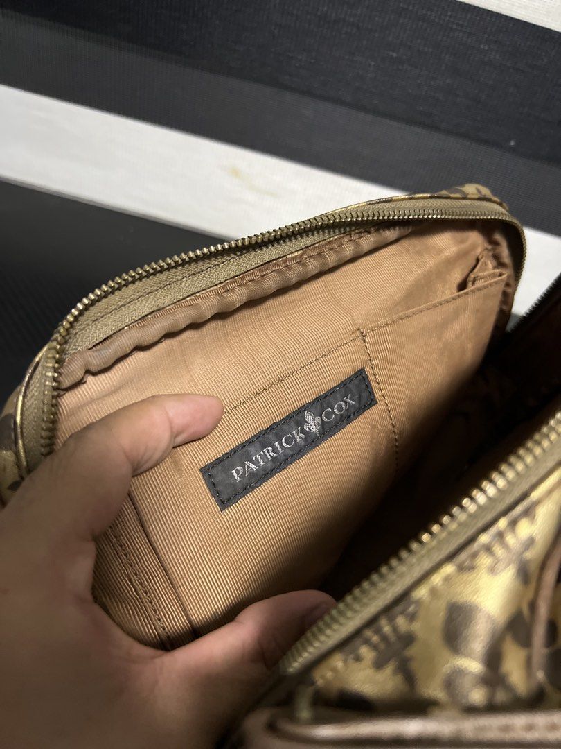 Patrick Cox Monogram Crossbody Bag Gold Brown (Category: Luxury Bags & Wallets) located in Calasiao. Submitted by pb.supply_v2 (Listing ID 1468050840, Image 3). Description: Patrick Cox crossbody bag in gold and brown tones. All-over fleur-de-lis monogram pattern printed on the exterior. Dual zip compartments up top with a brown lining inside. Includes an adjustable strap and an interior slip pocket with the brand label stitched inside. Clean str
