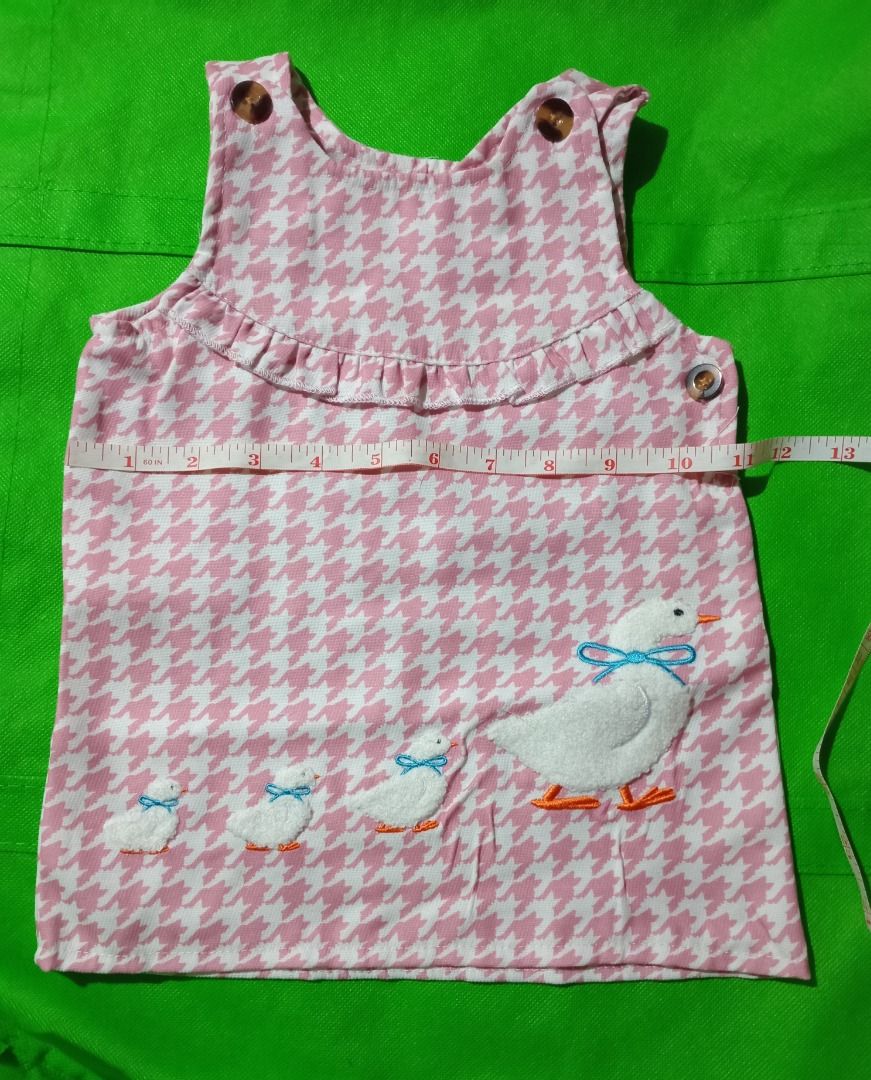 Pink and White Houndstooth Duck Tunic Top (Category: Other Babies Going Out Needs) located in Quezon City. Submitted by macon0948 (Listing ID 1467894228, Image 2). Description: - Pink and white houndstooth pattern - Adorable embroidered mother duck and ducklings with blue bows at the bottom - Sweet ruffle trim across the chest - Convenient button closures at the shoulders and side - Sleeveless design - Chest width: approx. 13 inches.