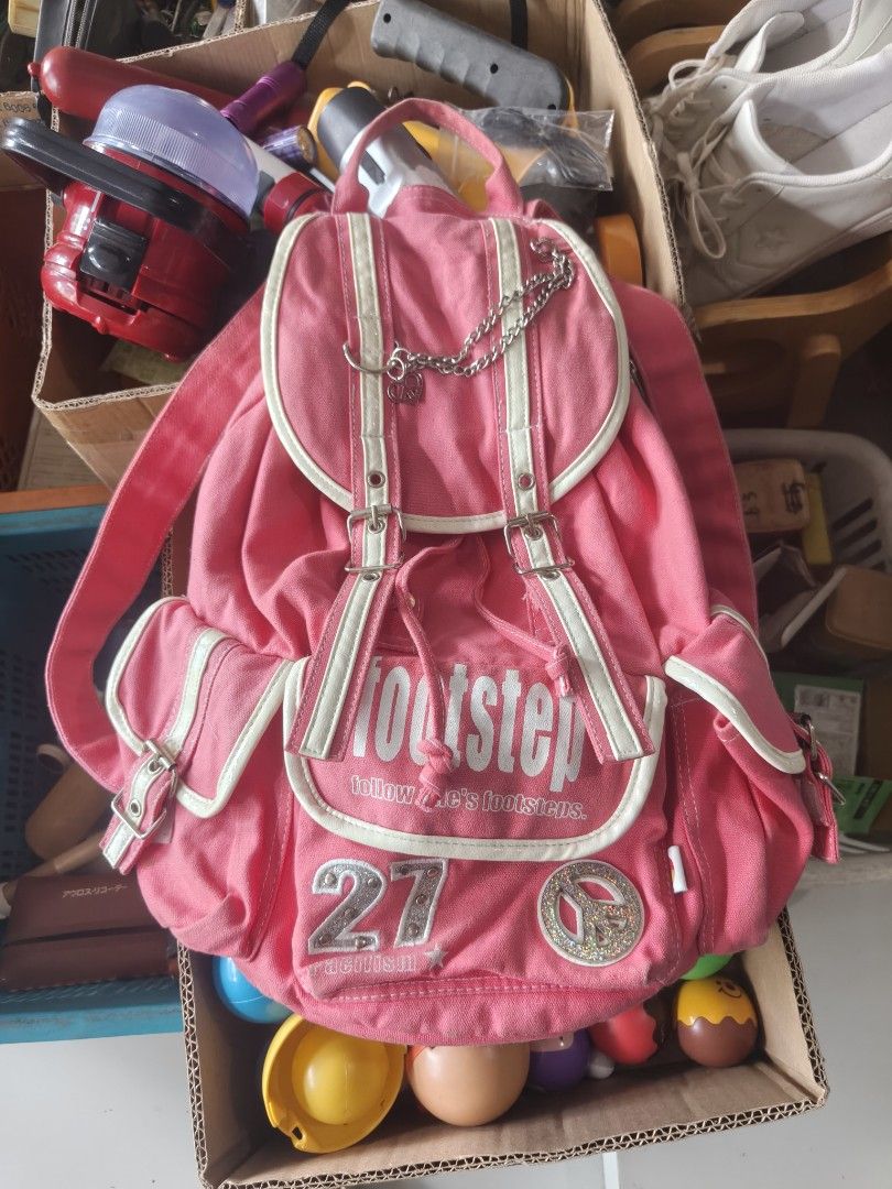 Pink Canvas Footstep Backpack with Chain and Patches (Category: Backpacks) located in Binan City. Submitted by makinpeso0622 (Listing ID 1467876174, Image 1). Description: - Color: Bright pink canvas - Design: 'Footstep', number 27, and peace sign patches with metal chain detail - Closure: Drawstring with double buckled straps - Pockets: Convenient side pockets with buckles - Straps: Adjustable shoulder straps for comfort - Interior: Clean white 