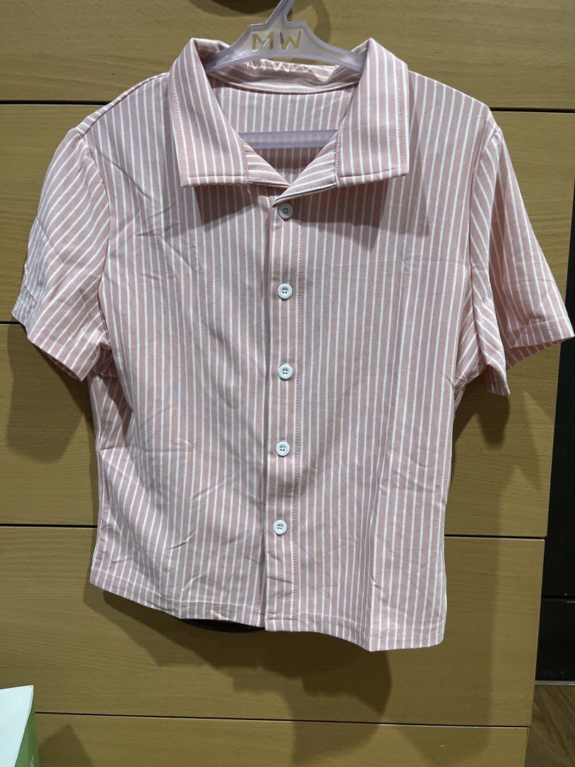 Pink Striped Short Sleeve Button Up Collared Shirt (Category: Shirts) located in Quezon City. Submitted by zinniemon (Listing ID 1467904981, Image 1). Description: - Cute pink and white striped design - Collared neckline with a button-down front and white buttons - Comfortable boxy, casual fit - Lightweight and breathable fabric - Perfect for everyday wear and easy to pair with jeans or shorts.