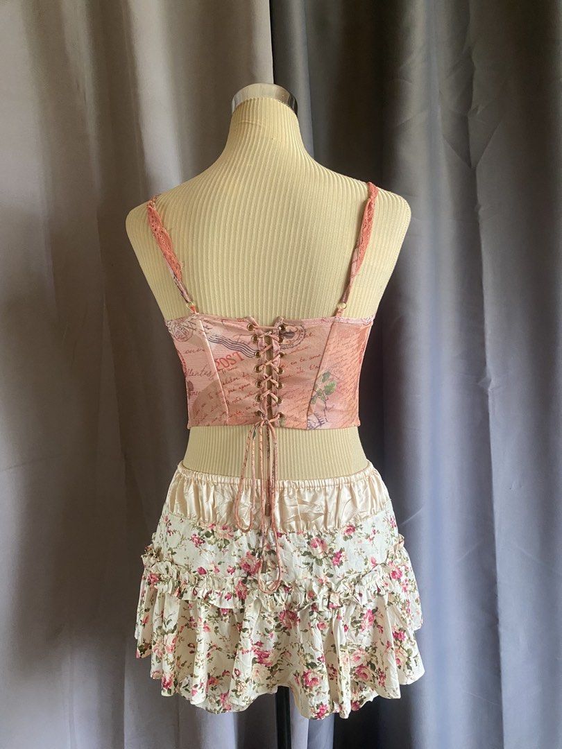 Outcast Pink Vintage Postcard Keyhole Corset Top (Category: Sleeveless) located in Cagayan de Oro. Submitted by curated_closetph (Listing ID 1467937897, Image 3). Description: — Size : M - L — Color: Pink / Peach — Vintage postcard and stamp print for a retro aesthetic — Upper bust keyhole cutout detail — Underwire cups for support and shaping — Adjustable spaghetti straps with delicate lace trim — Lace-up ribbon back with metal grommets — Pointe