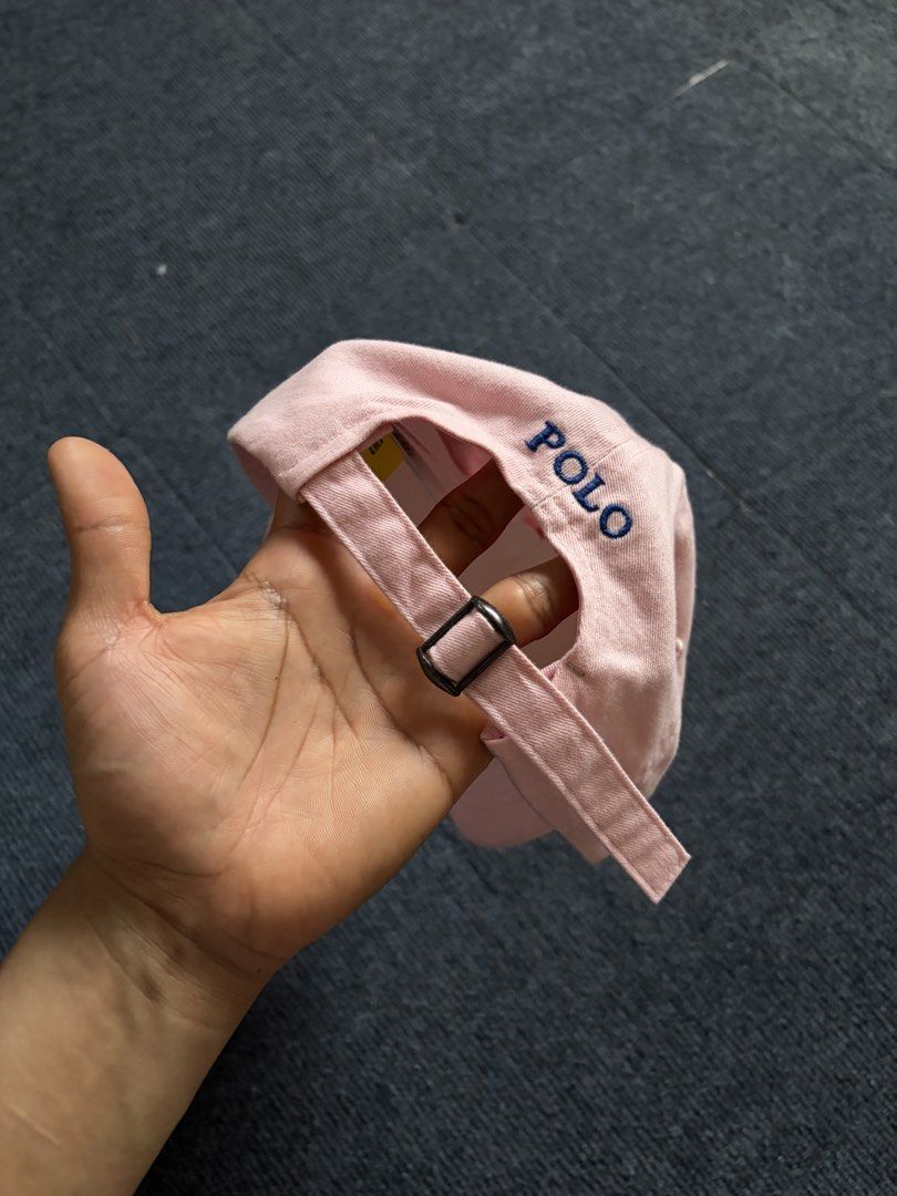 Polo Ralph Lauren Pink Baseball Cap (Category: Caps & Hats) located in Manila. Submitted by toys_hats005 (Listing ID 1467957593, Image 2). Description: - Brand: Polo Ralph Lauren - Color: Pink with dark blue embroidered pony logo - Material: 100% cotton - Fit: Adjustable strap at the back with metal buckle - Details: 'POLO' lettering embroidered above the back strap - Condition: Pristine, clean fabric, with original internal tags and structure in
