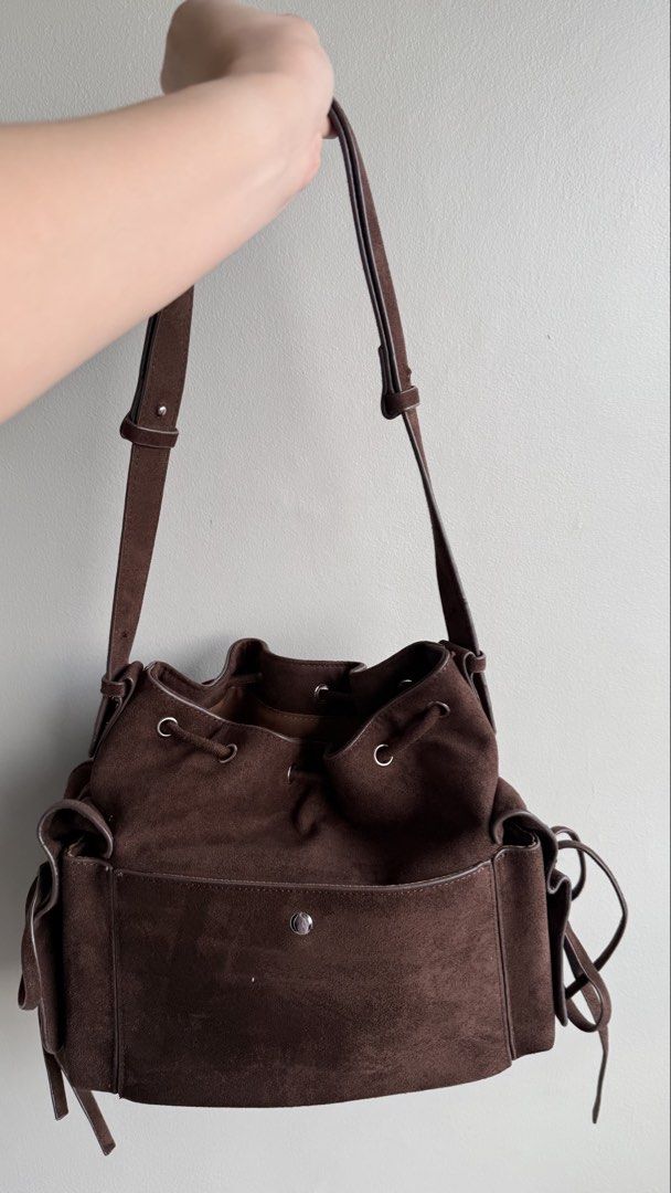 Pony Twenty Eight Suede Bucket Bag (Category: Shoulder Bags) located in Pasay City. Submitted by maviemavz (Listing ID 1467893397, Image 3). Description: - Material: Brown suede with brown fabric interior lining - Closure: Secure drawstring top with silver hardware - Exterior: Side pockets accented with cute tiny heart charms - Strap: Adjustable shoulder strap for a custom fit - Interior: Includes a zipper pocket and slip pockets for organization
