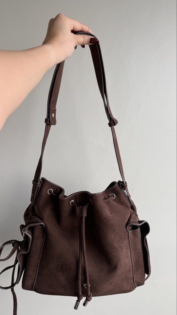 Pony Twenty Eight Suede Bucket Bag (Category: Shoulder Bags) located in Pasay City. Submitted by maviemavz (Listing ID 1467893397, Image 1). Description: - Material: Brown suede with brown fabric interior lining - Closure: Secure drawstring top with silver hardware - Exterior: Side pockets accented with cute tiny heart charms - Strap: Adjustable shoulder strap for a custom fit - Interior: Includes a zipper pocket and slip pockets for organization