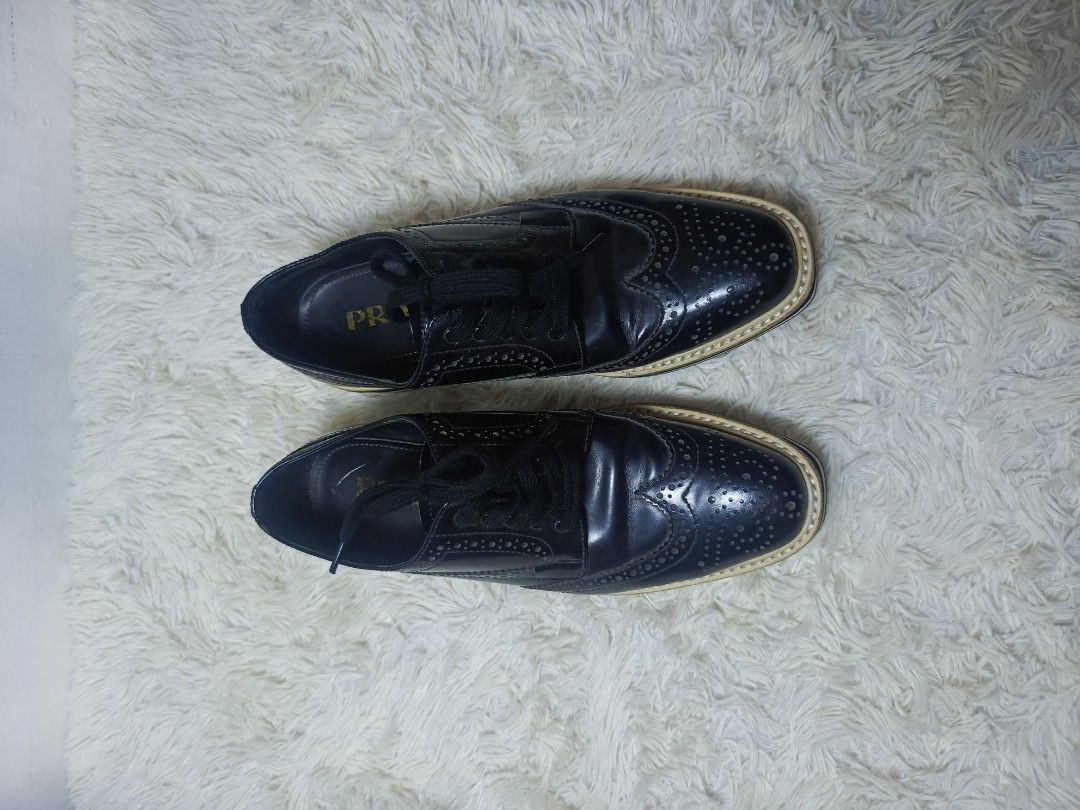 PRADA LEATHER BROGUE PLATFORM SHOES (Category: Loafers) located in Baguio. Submitted by 074thriftmania (Listing ID 1467962956, Image 2). Description: - Brand: Prada - Style: Black leather wingtip brogues with thick flatform soles - Size: 6 (marked on bottom) - Details: Classic perforated patterns, front lace-up closure, gold Prada branding on insoles and embossed on rubber outsoles - Condition: Soles show light dirt marks from previous wear.