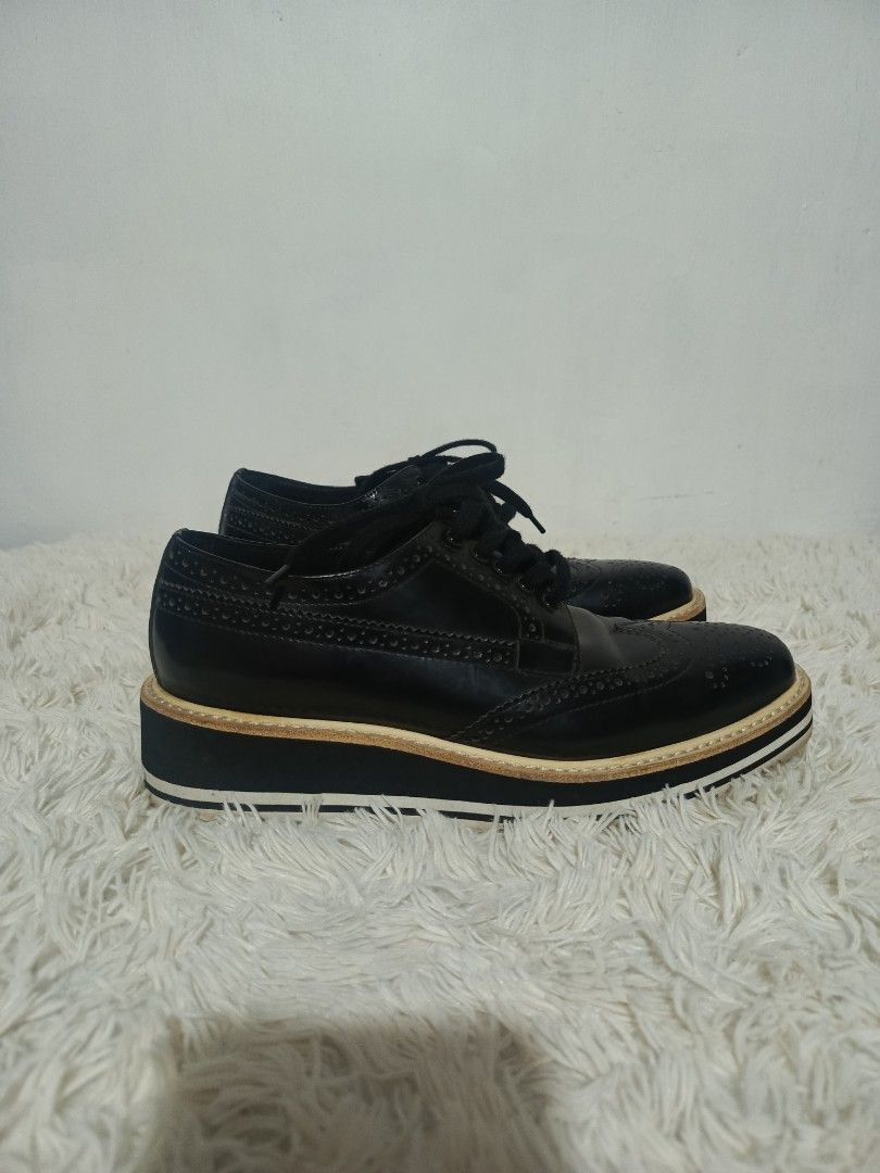 PRADA LEATHER BROGUE PLATFORM SHOES (Category: Loafers) located in Baguio. Submitted by 074thriftmania (Listing ID 1467962956, Image 1). Description: - Brand: Prada - Style: Black leather wingtip brogues with thick flatform soles - Size: 6 (marked on bottom) - Details: Classic perforated patterns, front lace-up closure, gold Prada branding on insoles and embossed on rubber outsoles - Condition: Soles show light dirt marks from previous wear.