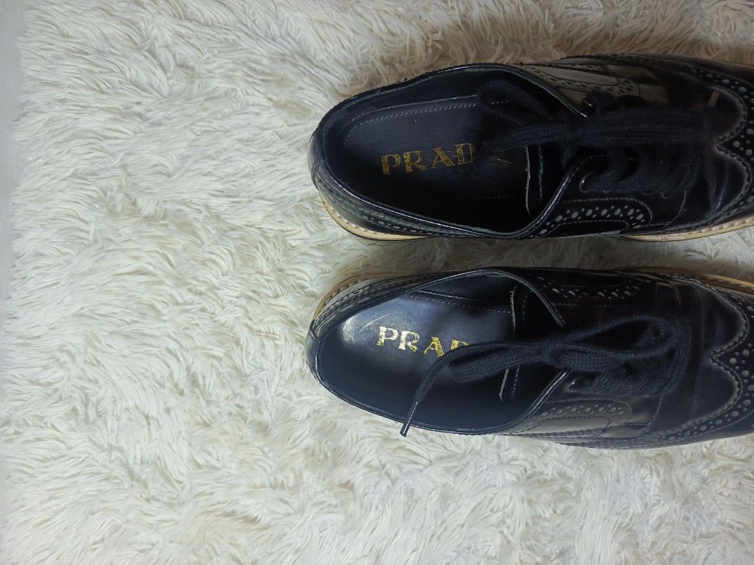 PRADA LEATHER BROGUE PLATFORM SHOES (Category: Loafers) located in Baguio. Submitted by 074thriftmania (Listing ID 1467962956, Image 3). Description: - Brand: Prada - Style: Black leather wingtip brogues with thick flatform soles - Size: 6 (marked on bottom) - Details: Classic perforated patterns, front lace-up closure, gold Prada branding on insoles and embossed on rubber outsoles - Condition: Soles show light dirt marks from previous wear.