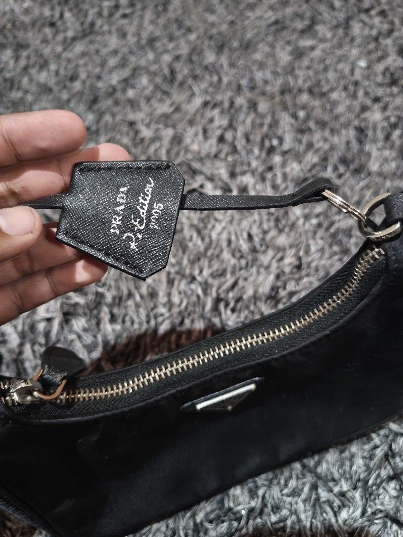 Prada Re-Edition 2005 Nylon Black Shoulder Bag (Category: Luxury Bags & Wallets) located in Laguindingan. Submitted by jingsuu22 (Listing ID 1467864446, Image 3). Description: - Brand: Prada Re-Edition 2005 - Color: Classic Black - Material: Durable signature nylon with silver-tone hardware - Features: Iconic metal triangle logo on front and matching detachable zipped pouch on the strap - Interior: Prada logo fabric lining with metal plaque label