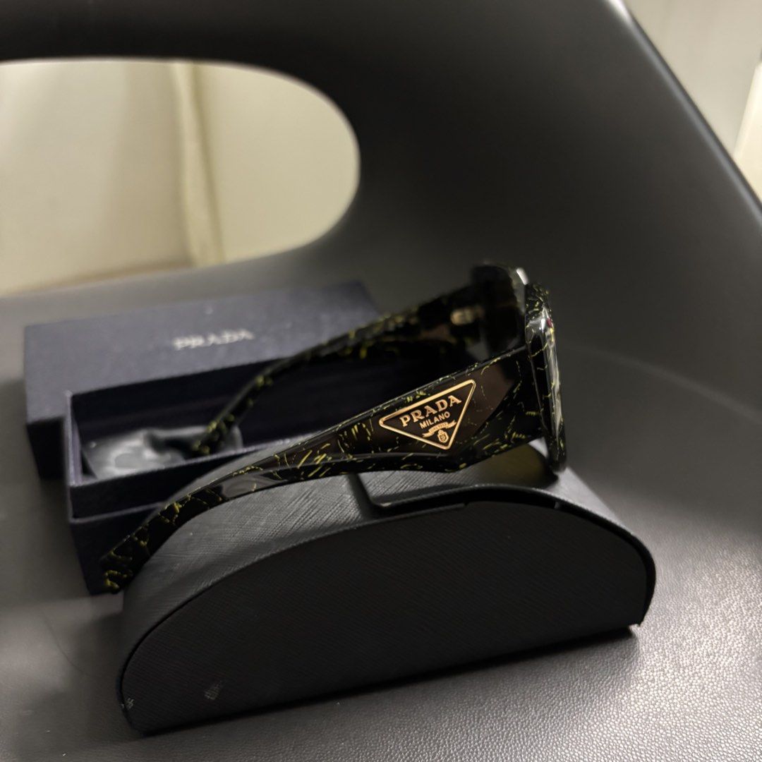 Prada Symbole (Category: Sunglasses & Eyewear) located in Makati City. Submitted by dianedelro (Listing ID 1467936332, Image 3). Description: - Brand: Prada - Model: Symbole Sunglasses - Colorway: Black with yellow marble/splatter pattern - Inclusions: Original Prada hard case, outer box, cleaning cloth, and documentation - Features iconic Prada triangular logo on the temples .