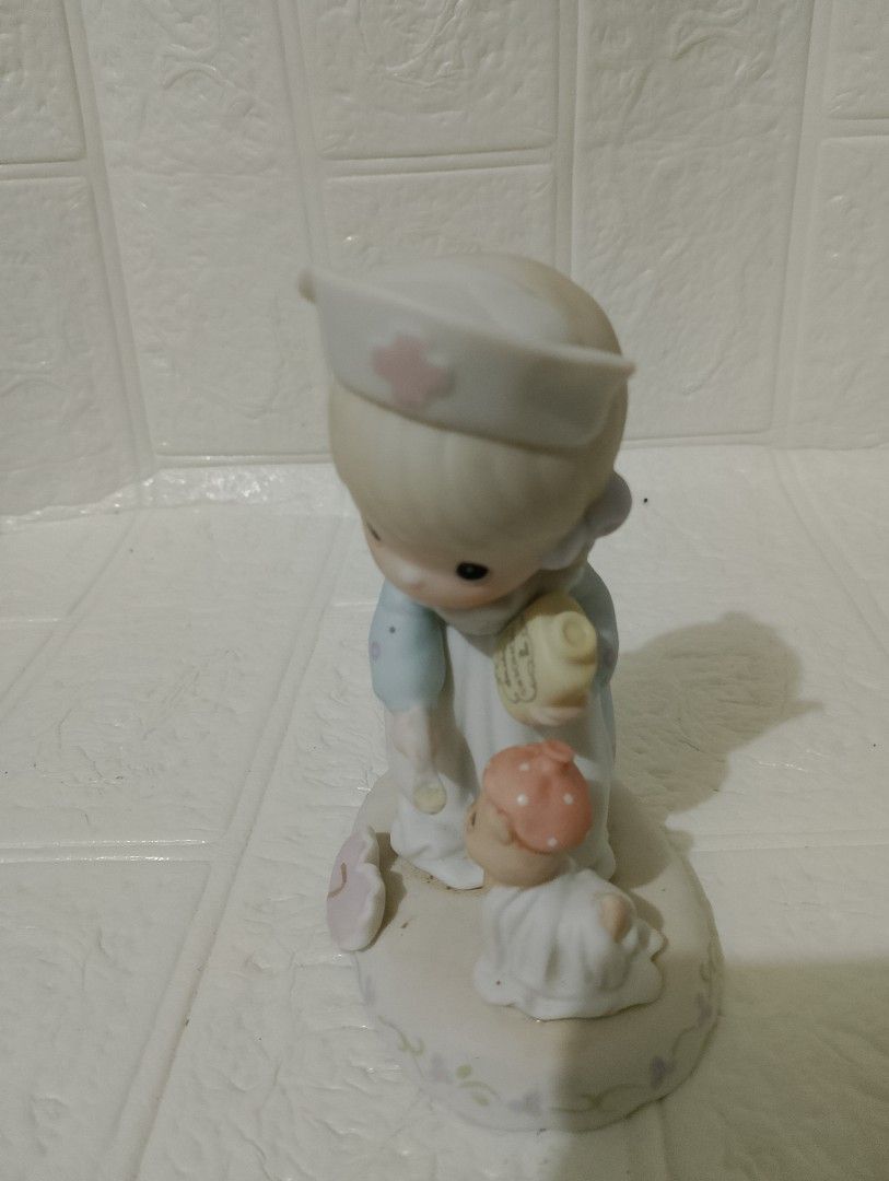Precious Moments (Category: Figurines & Statues) located in Manila. Submitted by alygudio (Listing ID 1467849497, Image 3). Description: - Authentic Precious Moments nurse figurine - Features a nurse feeding a tiny wrapped bear with Wonders Syrup - Charming pastel blue and white dress with purple ribbons - Unique heart-shaped base marked with the number 7 - Perfect for collectors or as a thoughtful gift.