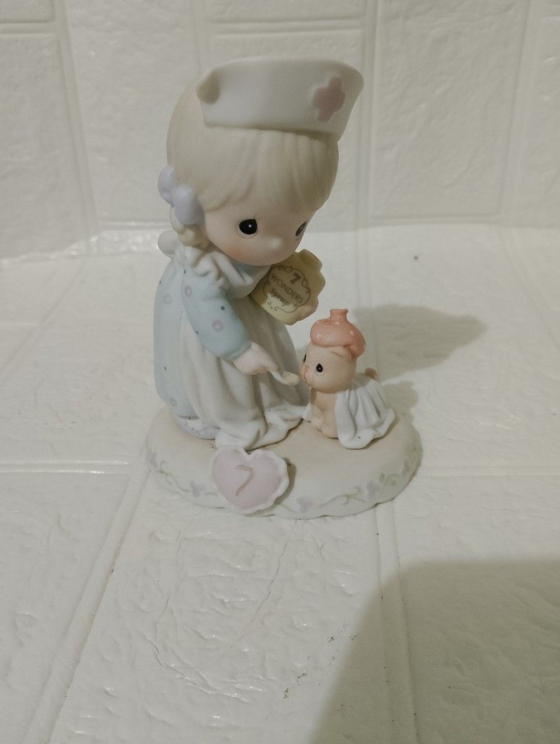 Precious Moments (Category: Figurines & Statues) located in Manila. Submitted by alygudio (Listing ID 1467849497, Image 1). Description: - Authentic Precious Moments nurse figurine - Features a nurse feeding a tiny wrapped bear with Wonders Syrup - Charming pastel blue and white dress with purple ribbons - Unique heart-shaped base marked with the number 7 - Perfect for collectors or as a thoughtful gift.