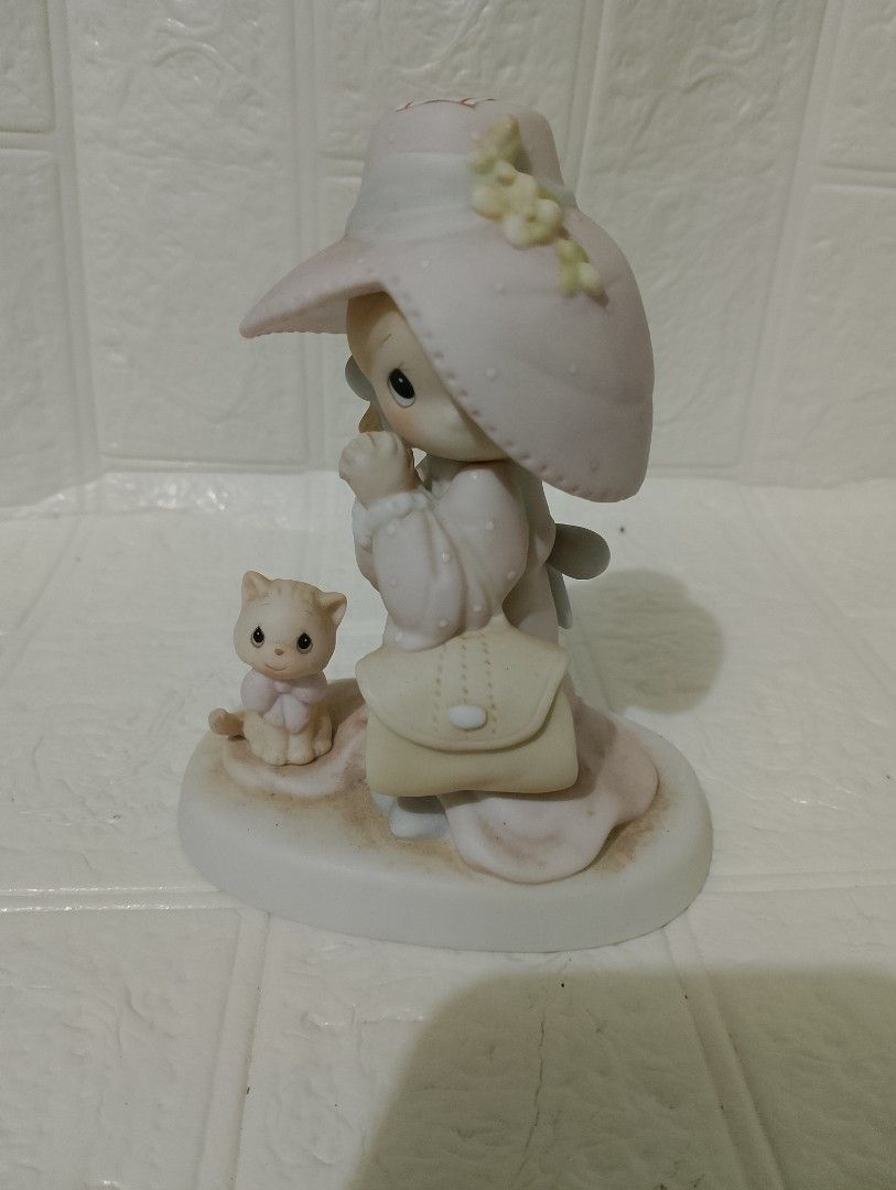Precious Moments Porcelain (Category: Figurines & Statues) located in Manila. Submitted by alygudio (Listing ID 1467849500, Image 1). Description: - Material: High-quality porcelain with a glossy finish - Design: Young girl in a wide-brimmed pink hat, holding a handbag, with a cute cat - Details: Soft pastel colors and a decorative ribbon at the back - Condition: Classic collectible piece - Ideal For: Shelf decor, display cabinets, or figurine co