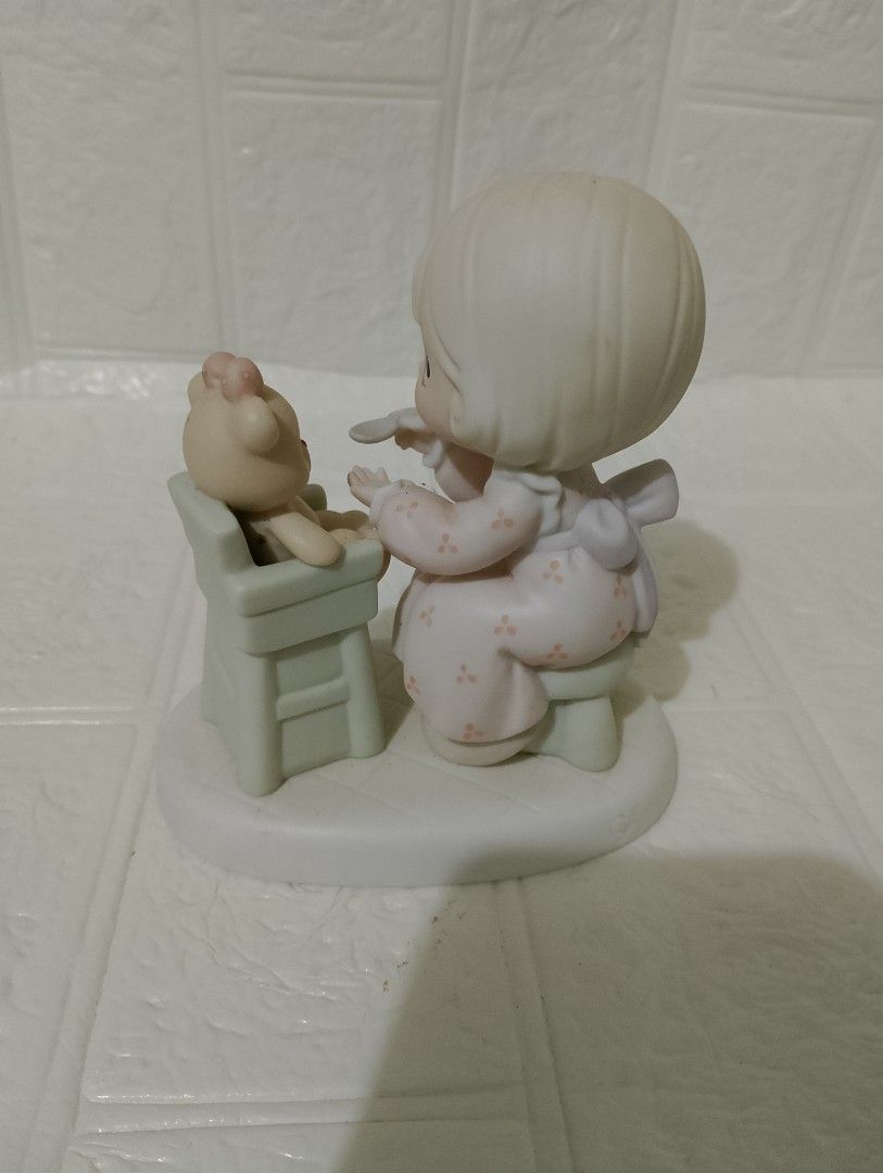 Precious Moments Porcelain (Category: Figurines & Statues) located in Manila. Submitted by alygudio (Listing ID 1467849502, Image 2). Description: - Authentic Precious Moments ceramic figurine - Features a young girl feeding a teddy bear in a high chair - Soft pastel pink and green colors on a white oval base - Detailed hand-painted facial features with iconic teardrop eyes - Classic porcelain collectible in well-kept, display-ready condition.