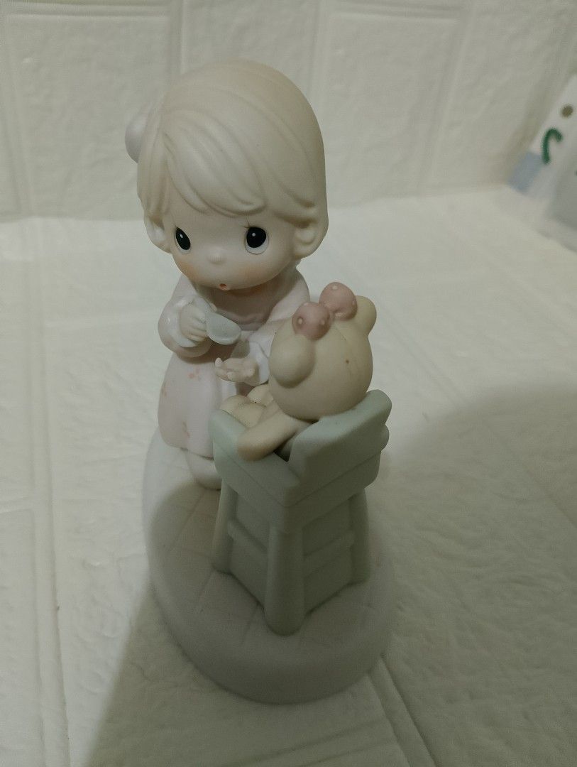 Precious Moments Porcelain (Category: Figurines & Statues) located in Manila. Submitted by alygudio (Listing ID 1467849502, Image 3). Description: - Authentic Precious Moments ceramic figurine - Features a young girl feeding a teddy bear in a high chair - Soft pastel pink and green colors on a white oval base - Detailed hand-painted facial features with iconic teardrop eyes - Classic porcelain collectible in well-kept, display-ready condition.