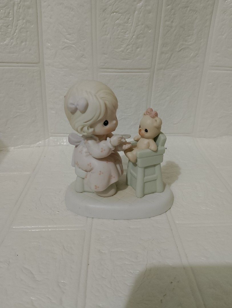 Precious Moments Porcelain (Category: Figurines & Statues) located in Manila. Submitted by alygudio (Listing ID 1467849502, Image 1). Description: - Authentic Precious Moments ceramic figurine - Features a young girl feeding a teddy bear in a high chair - Soft pastel pink and green colors on a white oval base - Detailed hand-painted facial features with iconic teardrop eyes - Classic porcelain collectible in well-kept, display-ready condition.