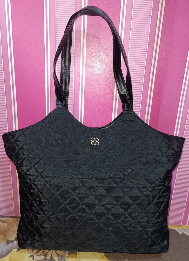 Preloved Black Quilted Tote Bag (Category: Tote Bags) located in Pasig City. Submitted by bcthriftedzoneonlineshop (Listing ID 1467881252, Image 2). Description: - Material: Shiny black nylon with stylish diamond stitching - Straps: Sturdy, secure dark shoulder straps for comfortable carrying - Design: Features a charming small gold four-leaf flower on the front - Interior: Roomy main compartment for all your daily essentials - Quality: Clean, du