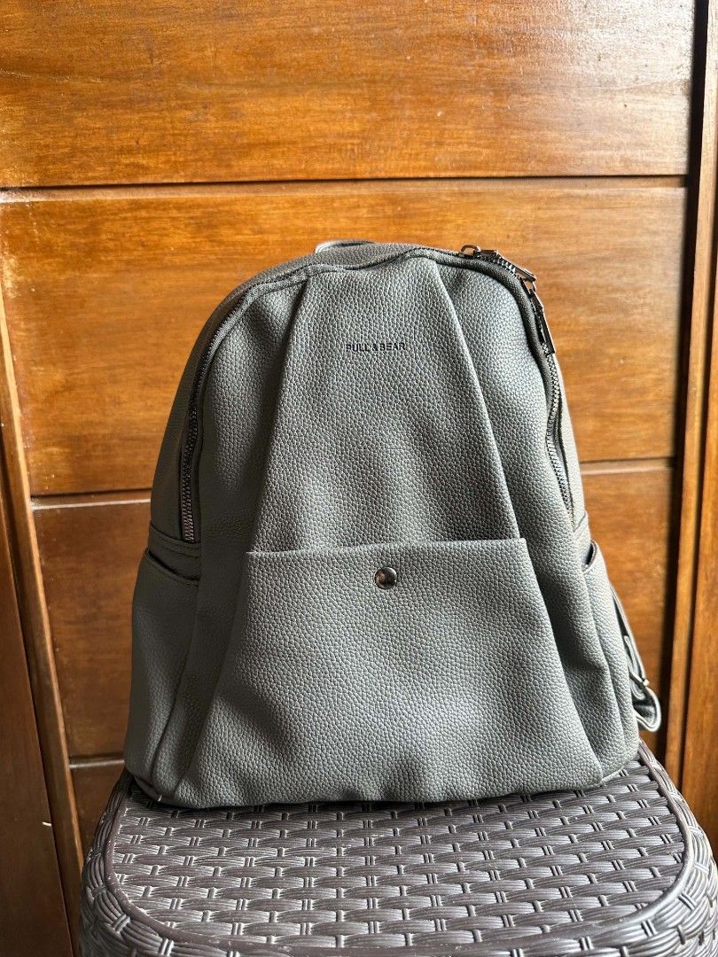 Pull&Bear Grey Faux Leather Backpack (Category: Backpacks) located in Rizal. Submitted by mayra74 (Listing ID 1467839645, Image 1). Description: - Brand: Pull&Bear - Material: Grey faux leather with pebbled texture - Pockets: Front flap pocket with snap closure, side pockets, and interior zip pocket - Closure: Main zipper compartment - Straps: Adjustable shoulder straps and top carry handle - Condition: Clean inside and out, well-maintained.