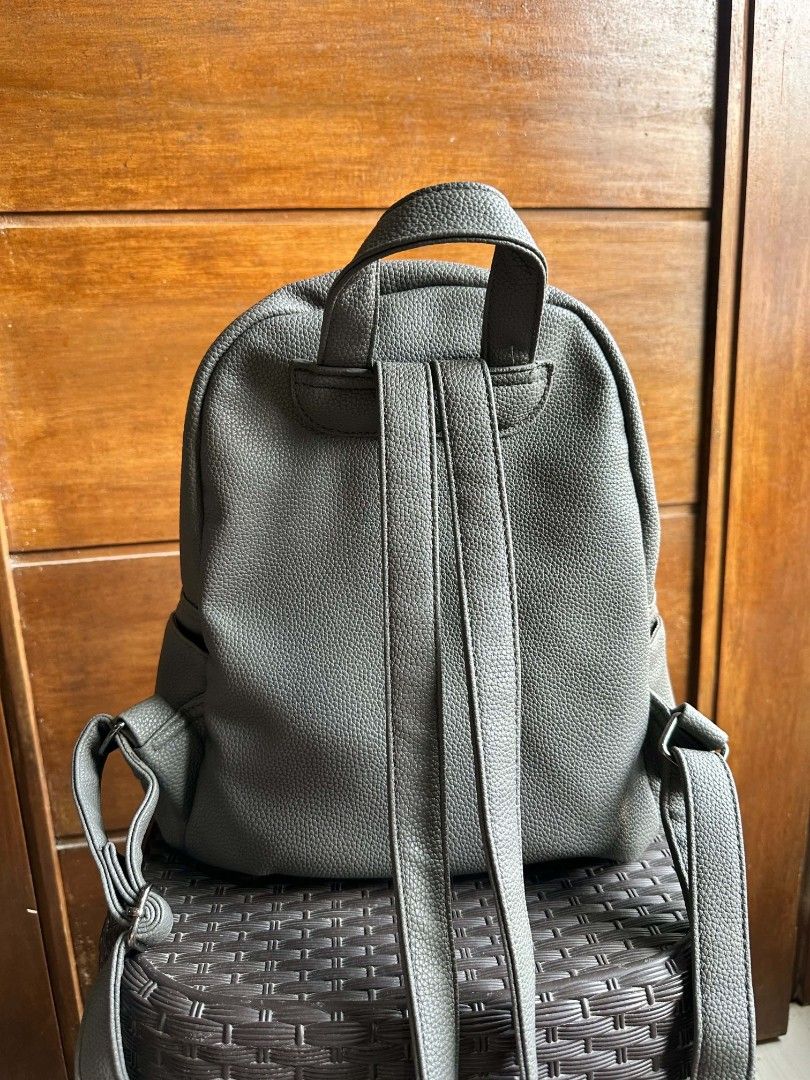 Pull&Bear Grey Faux Leather Backpack (Category: Backpacks) located in Rizal. Submitted by mayra74 (Listing ID 1467839645, Image 2). Description: - Brand: Pull&Bear - Material: Grey faux leather with pebbled texture - Pockets: Front flap pocket with snap closure, side pockets, and interior zip pocket - Closure: Main zipper compartment - Straps: Adjustable shoulder straps and top carry handle - Condition: Clean inside and out, well-maintained.