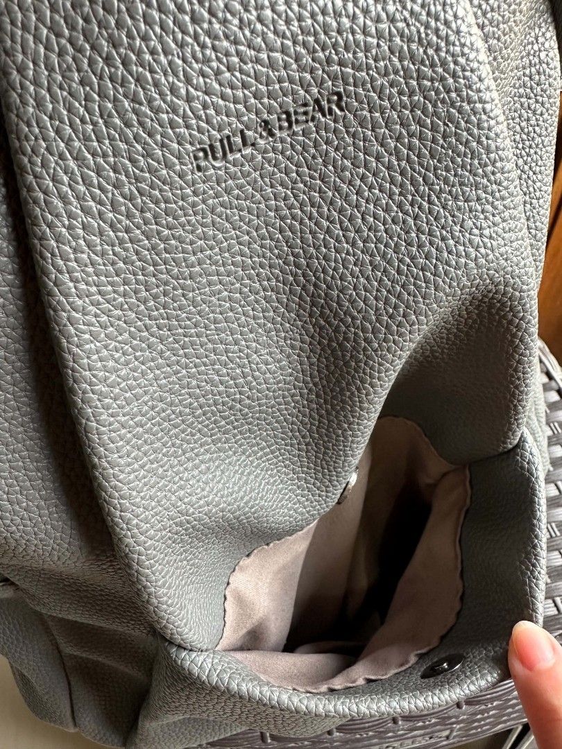 Pull&Bear Grey Faux Leather Backpack (Category: Backpacks) located in Rizal. Submitted by mayra74 (Listing ID 1467839645, Image 3). Description: - Brand: Pull&Bear - Material: Grey faux leather with pebbled texture - Pockets: Front flap pocket with snap closure, side pockets, and interior zip pocket - Closure: Main zipper compartment - Straps: Adjustable shoulder straps and top carry handle - Condition: Clean inside and out, well-maintained.