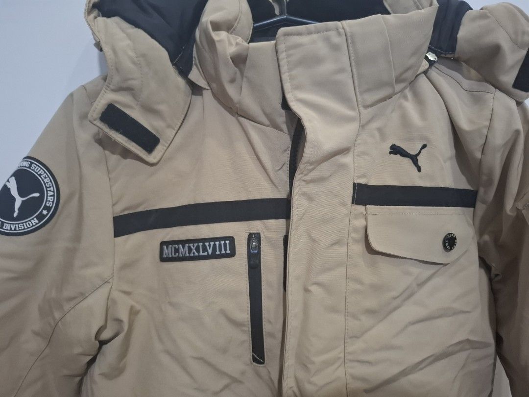 Puma Winter Jacket Beige Black Hooded Coat (Category: Babies & Kids Fashion) located in Imus. Submitted by maggieforce (Listing ID 1467922382, Image 3). Description: - size 120 on tag - Brand: Puma - Color: Tan with black contrast panels - Features: Hooded, thick padded lining for cold and snowy weather - Closure: Zip front with button flap - Pockets: Multiple functional pockets on chest and lower front - Details: Roman numerals graphic and Puma 