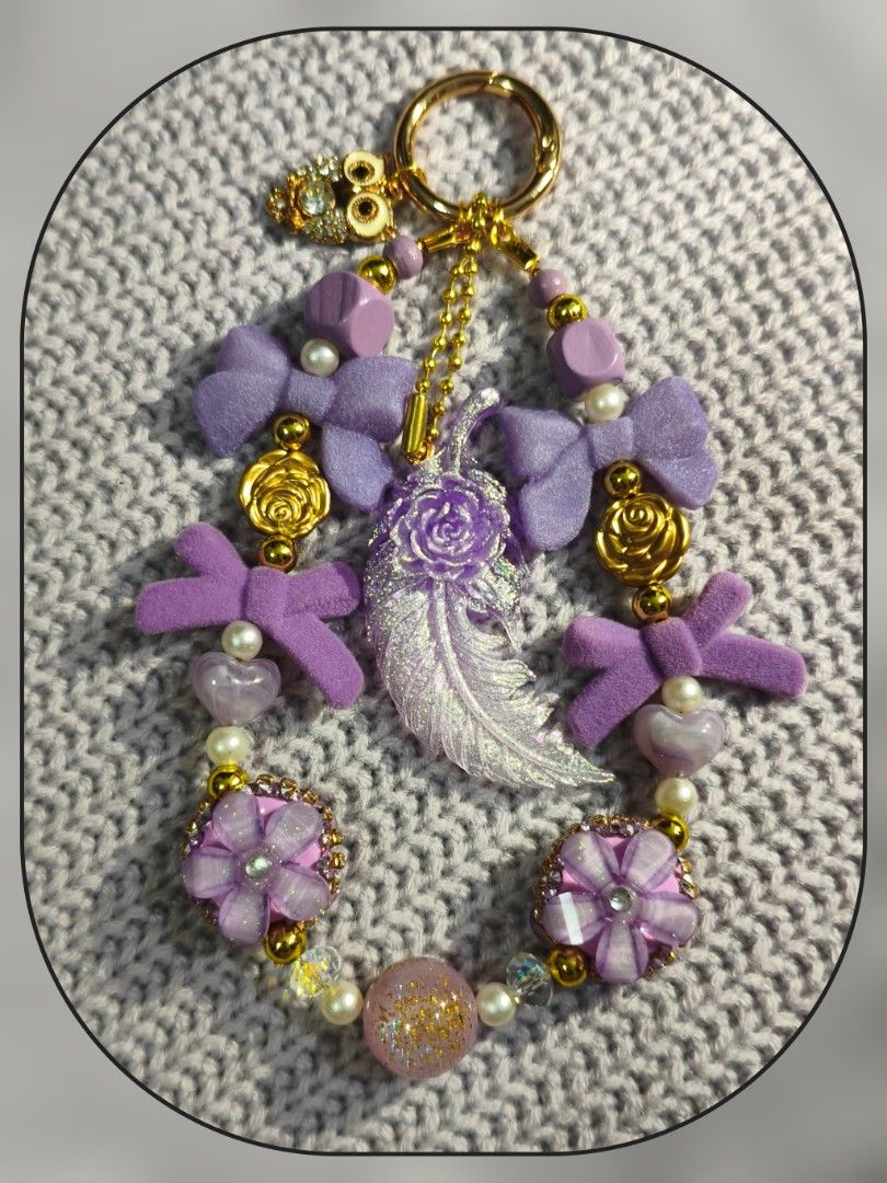 Purple Aesthetic Beaded Feather Owl Keychain (Category: Handmade Craft) located in Rizal. Submitted by cc_xixi (Listing ID 1468033808, Image 1). Description: - Handmade charm keychain in various shades of purple - Features fuzzy bows, metallic gold roses, pearl beads, and sparkly floral charms - Central translucent feather pendant with an embedded tiny rose - Accented with a small owl charm and secure gold clasp - Total length: Approximately 4 in