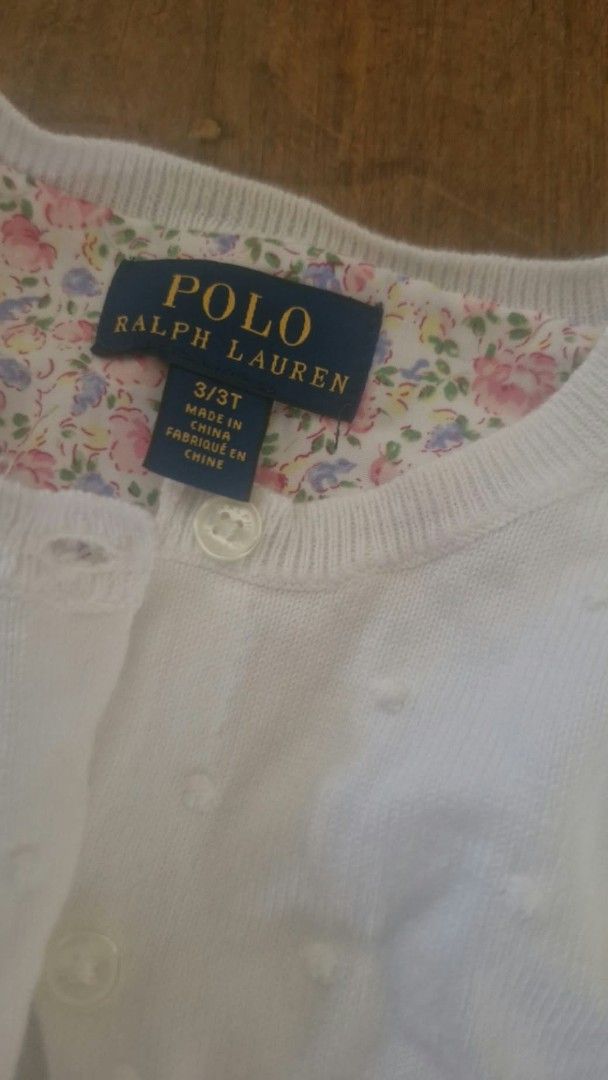 RALPH LAUREN RL White Cardigan (Category: Babies & Kids Fashion) located in Cebu City. Submitted by minimi.cebu (Listing ID 1467930451, Image 2). Description: - Brand: Polo Ralph Lauren - Size: 3T - Color: Clean white - Material/Texture: Knit fabric with subtle polka dot pattern - Details: Button-front closure and floral print lining inside the collar - Style: Lightweight layering piece, easy to match with any toddler outfit.