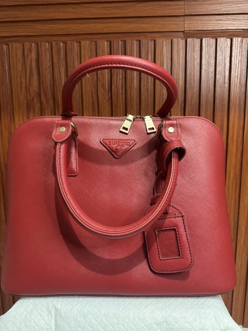 Red FANDISHE Leather Handbag (Category: Cross-body Bags) located in Imus. Submitted by budolfindsimus (Listing ID 1468003954, Image 1). Description: - Brand: Fandishe - Color: Vibrant Red - Material: Saffiano-style textured leather - Hardware: Premium gold-tone - Closure: Secure double top zip - Features: Dual top handles, matching luggage tag, and front triangle logo plaque - Design: Clean, structured shape in an ideal everyday size.