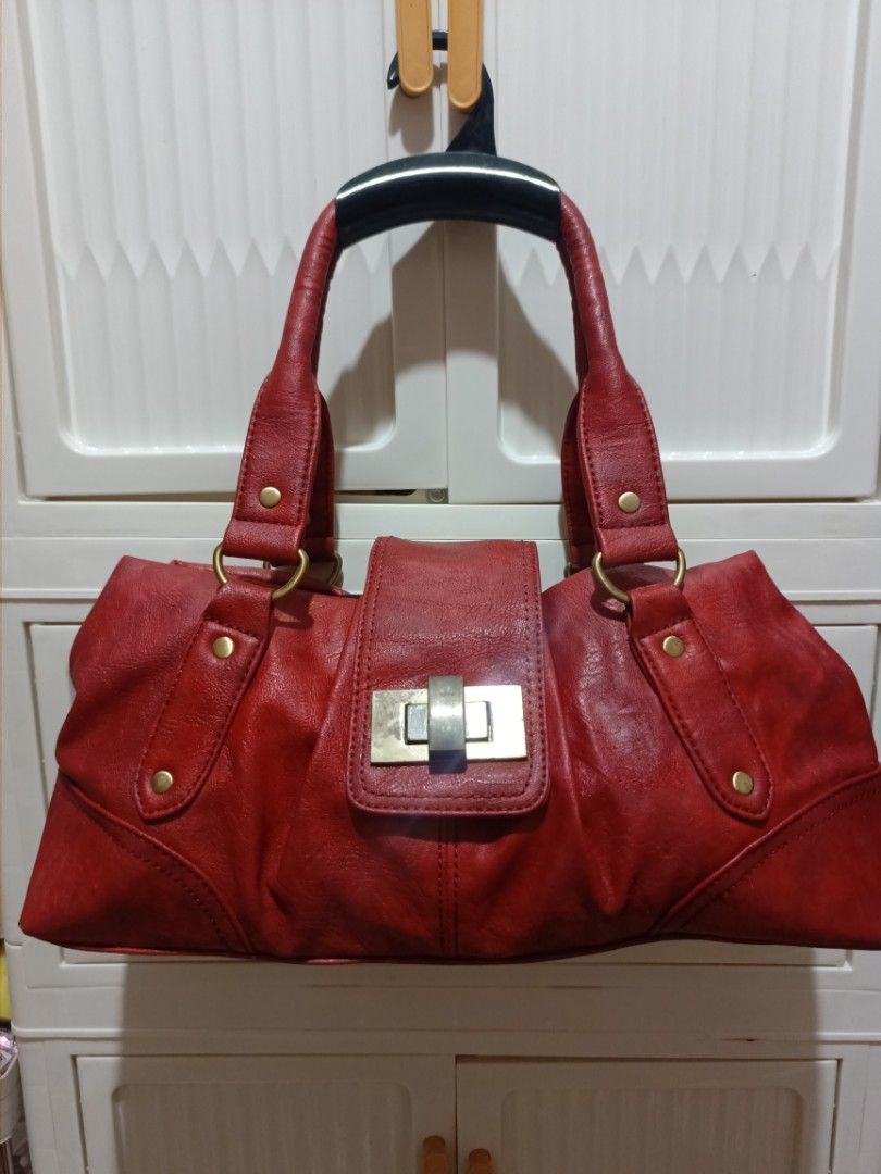 Red leather shoulder handbag with gold hardware (Category: Luxury Bags & Wallets) located in Manila. Submitted by del_thrifts03 (Listing ID 1467986784, Image 1). Description: - Color & Material: Red textured faux leather with dark fabric lining - Closure: Secure metal turn-lock on the front flap - Handles: Dual red handles with brass-toned rings and decorative studs - Interior: Roomy storage space with a built-in zipper compartment and side pocke