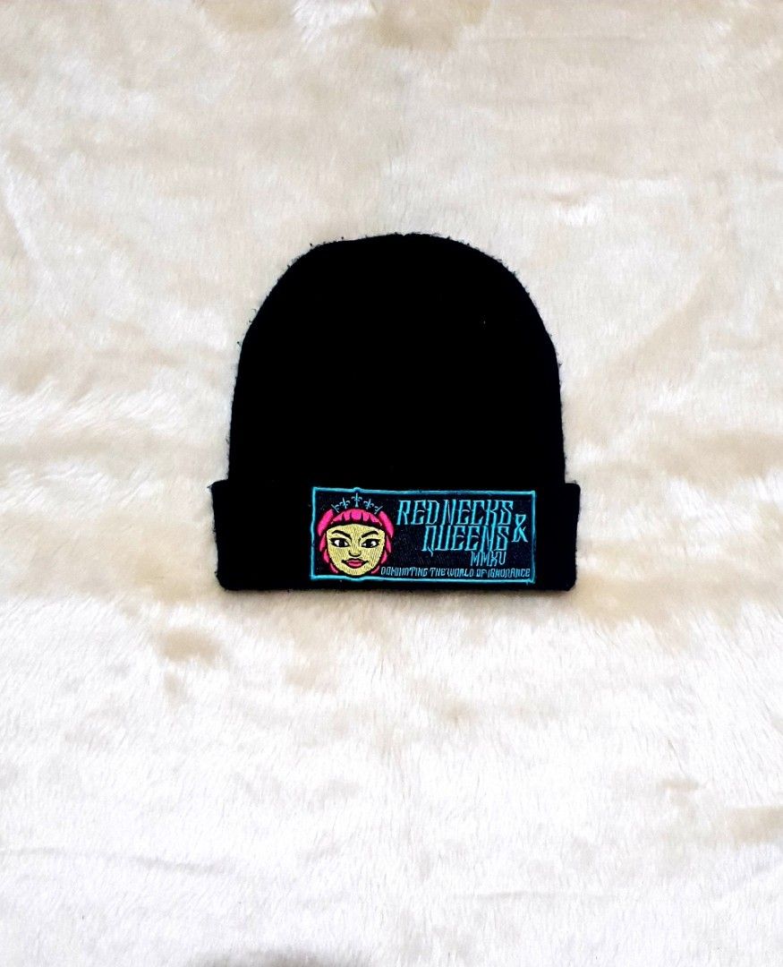 Red Necks & Queens Black Beanie Hat (Category: Caps & Hats) located in Taguig. Submitted by wethrifting2021 (Listing ID 1468014030, Image 1). Description: - Color: Black - Style: Knit beanie with folded brim - Details: Embroidered patch with cartoon face graphic, teal 'Red Necks & Queens MMXV' lettering, and 'Dominating The World Of Ignorance' tagline - Material: Thick, warm fabric ideal for cold weather - Condition: Excellent, interior tag intac