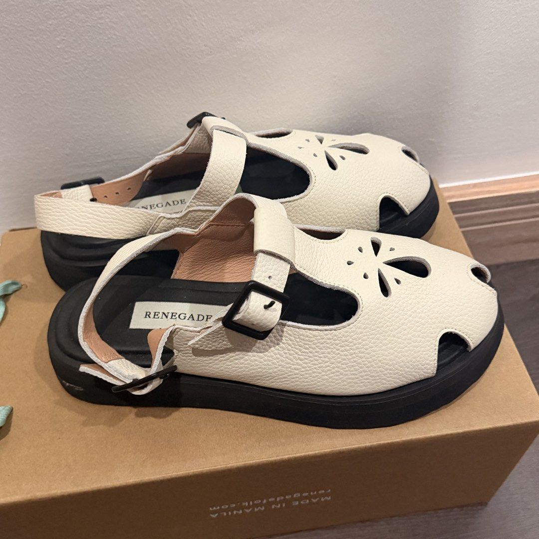 Renegade Folk White Leather Sandals (Category: Flats & Sandals) located in San Pedro. Submitted by love.bruce10 (Listing ID 1467898292, Image 3). Description: - Brand: Renegade Folk - Color: White with textured leather finish - Design: Closed-toe style featuring cute cutout flower patterns and adjustable buckle straps - Sole: Sturdy black lug soles with excellent tread grip - RFS too small - Inclusions: Comes with the original box - Condition: Ex