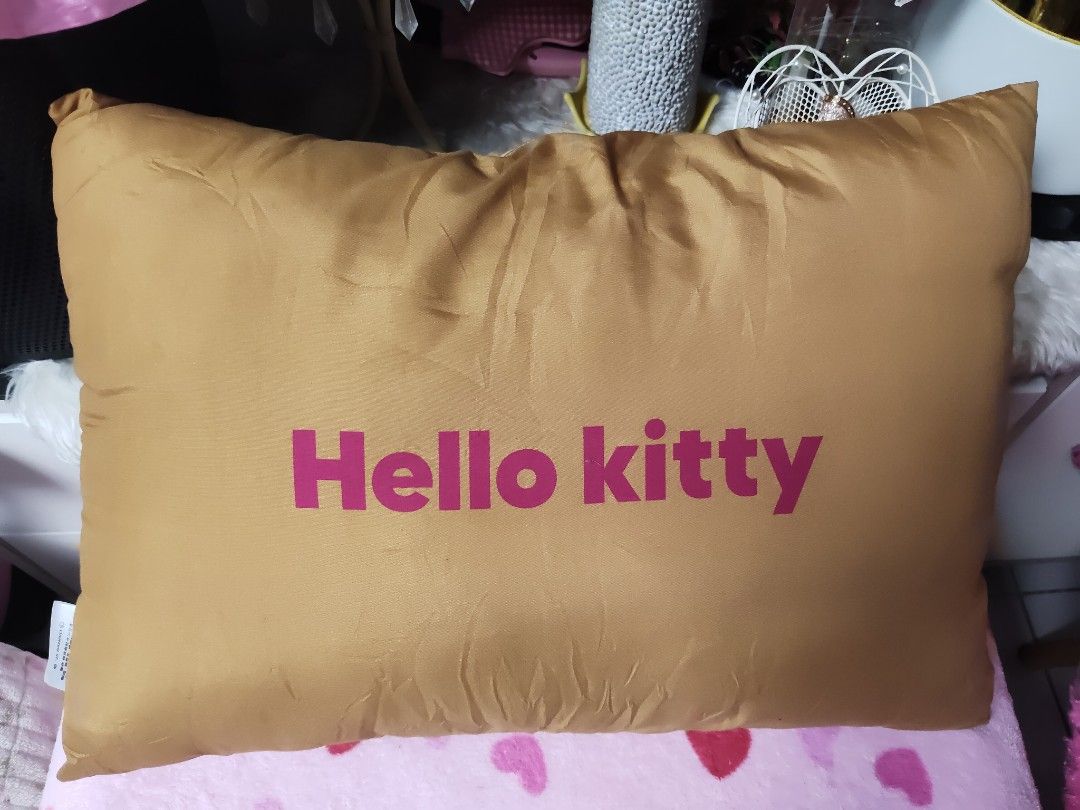 Sanrio Hello Kitty Brown Decorative Cushion Pillow (Category: Cushions & Throws) located in Pasay City. Submitted by ynamariie (Listing ID 1467841981, Image 2). Description: Sanrio Kitty brown cushion pillow. Front displays Kitty face with a large pink flower and yellow star accent. Back features bold Kitty text in pink. Tag reads '25 SANRIO. Made in China. For sale in Japan only. Soft fabric material, great room decor piece. Size : 18x13.
