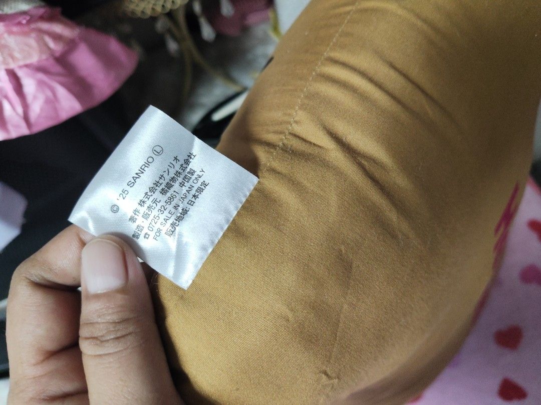 Sanrio Hello Kitty Brown Decorative Cushion Pillow (Category: Cushions & Throws) located in Pasay City. Submitted by ynamariie (Listing ID 1467841981, Image 3). Description: Sanrio Kitty brown cushion pillow. Front displays Kitty face with a large pink flower and yellow star accent. Back features bold Kitty text in pink. Tag reads '25 SANRIO. Made in China. For sale in Japan only. Soft fabric material, great room decor piece. Size : 18x13.