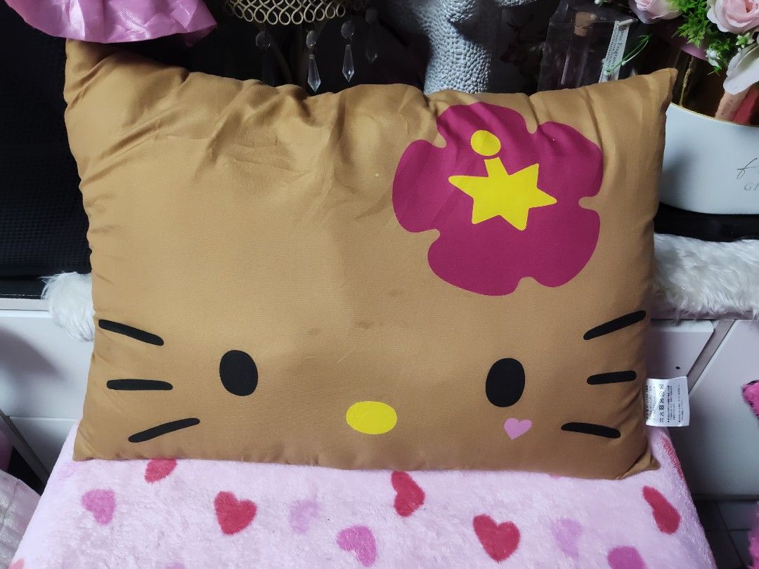 Sanrio Hello Kitty Brown Decorative Cushion Pillow (Category: Cushions & Throws) located in Pasay City. Submitted by ynamariie (Listing ID 1467841981, Image 1). Description: Sanrio Kitty brown cushion pillow. Front displays Kitty face with a large pink flower and yellow star accent. Back features bold Kitty text in pink. Tag reads '25 SANRIO. Made in China. For sale in Japan only. Soft fabric material, great room decor piece. Size : 18x13.