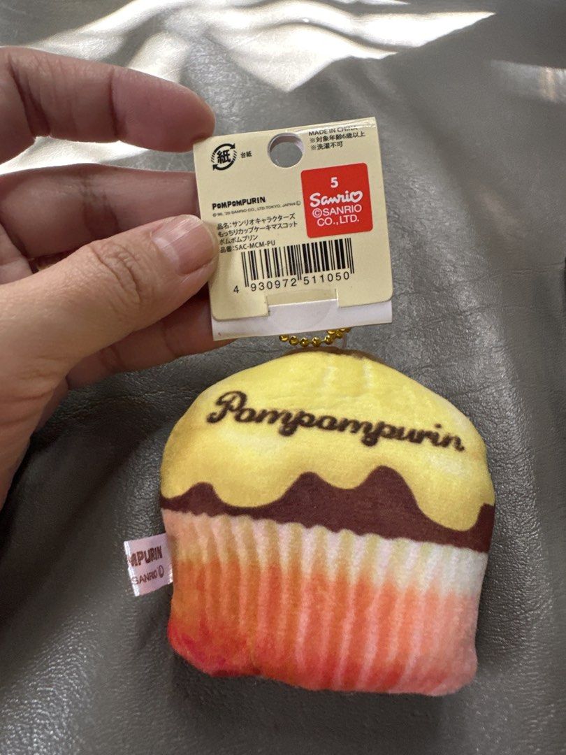 Sanrio Pompompurin Cupcake Mascot Plush Keychain (Category: Plushies & Soft Toys) located in Cainta. Submitted by shopbyyna (Listing ID 1467876987, Image 2). Description: - Official Sanrio Pompompurin cupcake mascot plush - Super soft, squishy texture in classic yellow and brown - Features adorable brown hat detail and 'Pompompurin' text printed on the back - Includes a gold ball chain for easy hanging on bags or keys - Comes with original cardbo