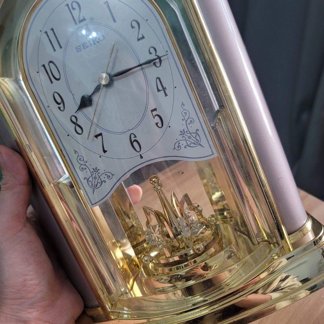 Seiko Gold Tone Mantel Clock With Rotating Pendulum (Category: Clocks) located in Pasig City. Submitted by bunny.bella (Listing ID 1467916087, Image 2). Description: - Brand: Seiko - Design: Pale pink body with elegant gold-tone trim and arched glass front - Dial: Classic white face with black Arabic numerals and ornate corner accents - Special Feature: Beautiful rotating crystal pendulum inside - Power: Battery-operated - Ideal for: Mantle piece