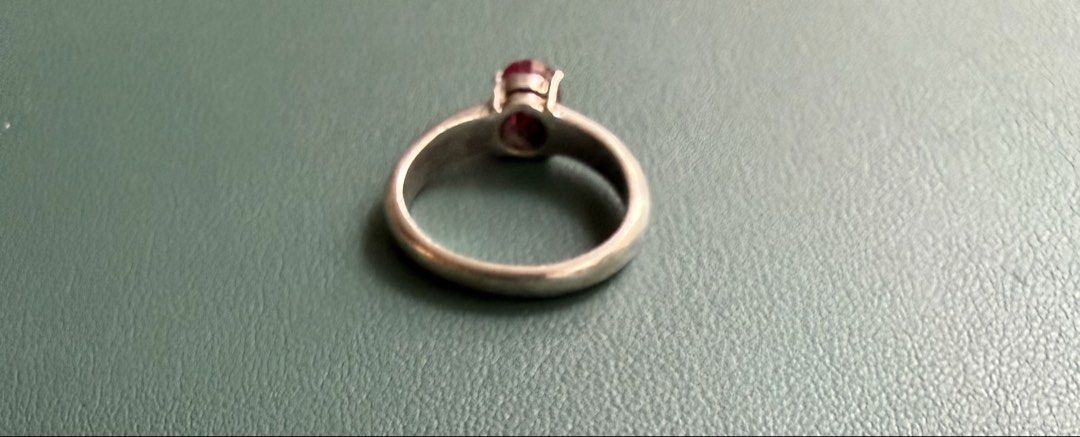 Silver Ring With Ruby Gemstone (Category: Rings) located in Singapore. Submitted by car12927 (Listing ID 1467903079, Image 2). Description: - Classic silver ring featuring a vibrant oval red gemstone - Size: Approximately 1 cm inner diameter - Secure prong setting keeps the stone firmly in place - Charming vintage appeal with visible metal wear and natural patina - Simple, timeless design perfect for everyday wear.