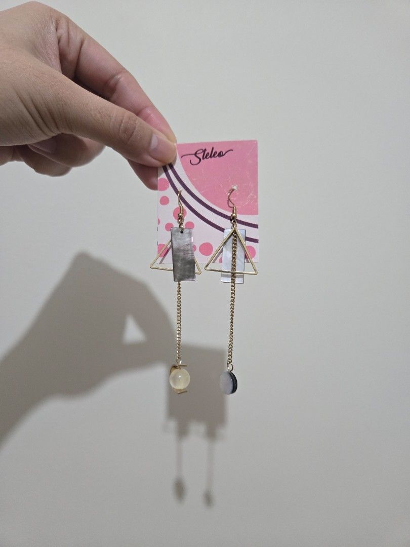 Steleo asymmetric dangling earrings (Category: Earrings) located in Pasay City. Submitted by samcas (Listing ID 1467952904, Image 3). Description: Brand new Steleo asymmetric dangling earrings in gold-tone hardware. Features dark stones, geometric shapes, thin chains, a pearl ball, and a round pendant. Comes on original backing card. Perfect statement piece!.