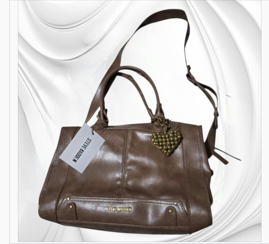 Steve Madden Brown Satchel Bag With Heart Charm (Category: Shoulder Bags) located in Paranaque City. Submitted by calm_youngstore7 (Listing ID 1468024095, Image 3). Description: - Brand: Steve Madden - Color: Classic Brown - Condition: Brand new with original store tags attached - Features: Dual top handles, long adjustable shoulder strap, secure zipper closure, and stylish side snap details - Hardware: Gold/brass-toned hardware - Extras: Adorabl